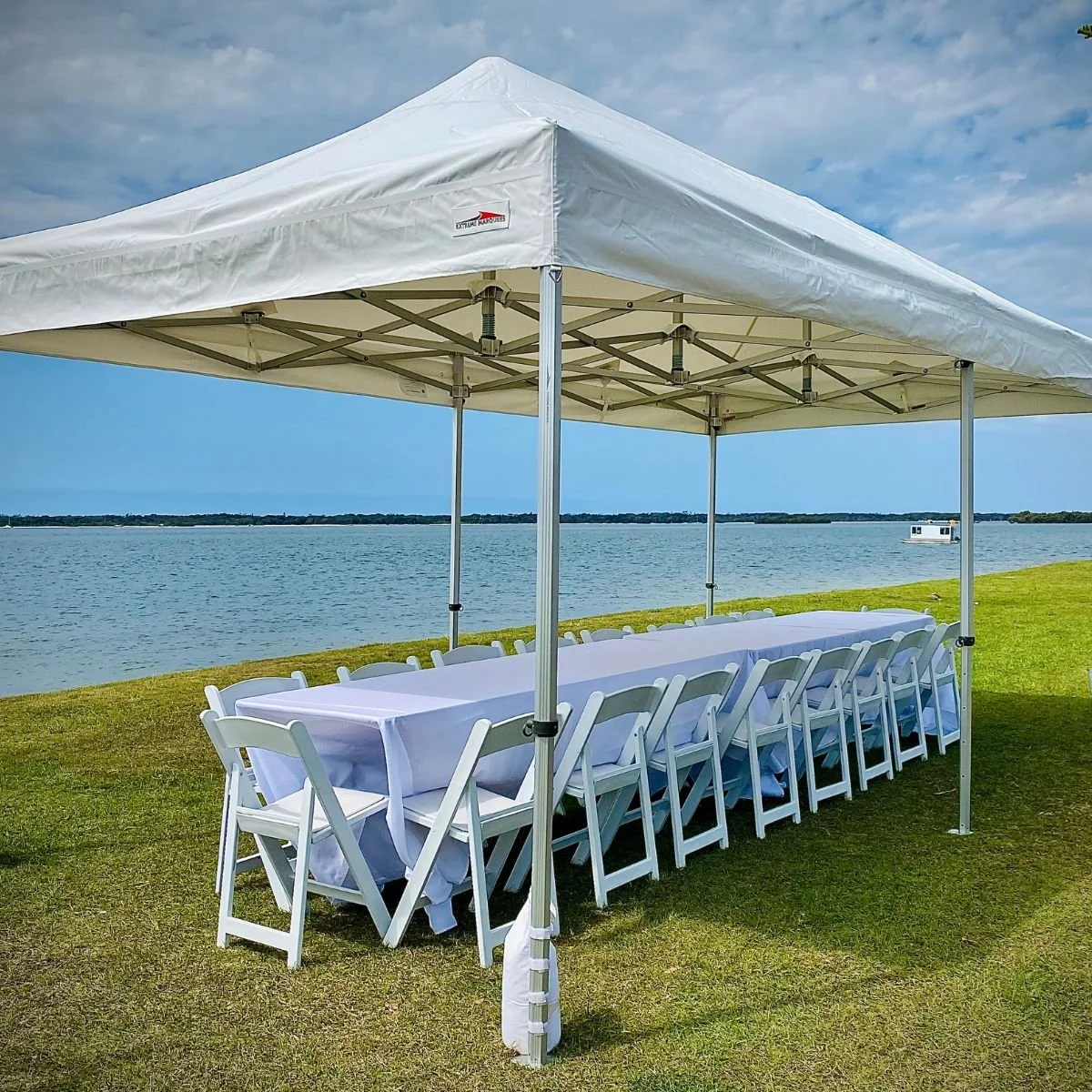 Event marquee hire by Stay Golden Event Hire on the Gold Coast: white canopy tent, long table and white chairs by the water.