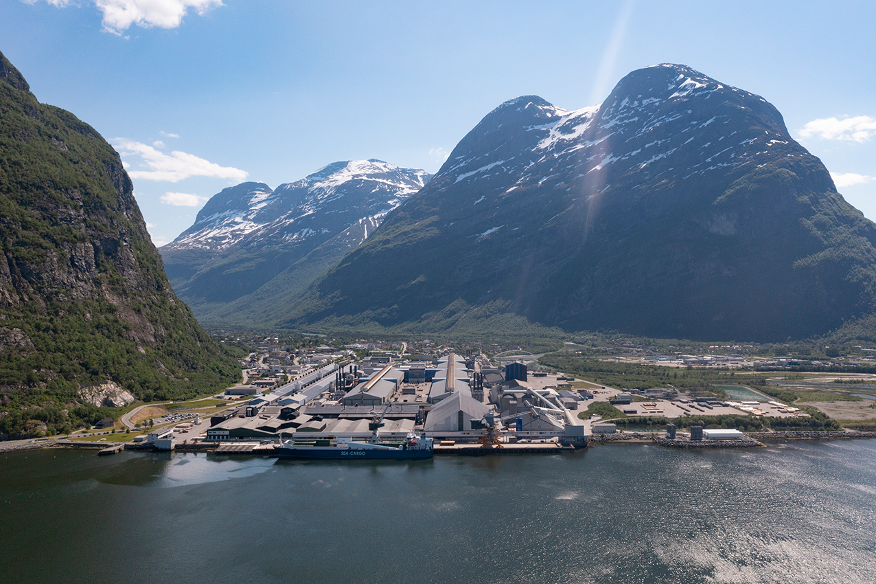 Dronebilde av Sunndal og industriområdet der Langset Mek holder til. Bildet viser vakre fjell og fjorden, det er blå himmel og sol