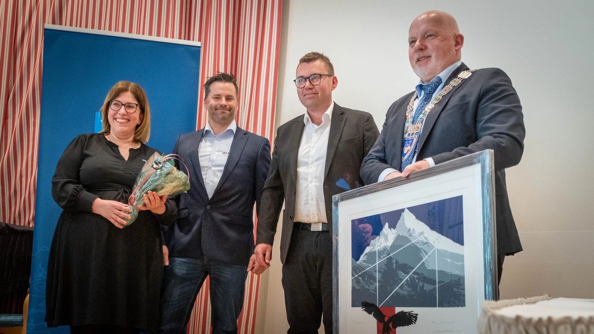 23.04.25 kunne vi stolt ta i mot Mangfolds- og inkluderingsprisen 2024 i Møre og Romsdal. Bildet viser to ansatte i Langset Mek som mottar prisen og et innrammet bilde fra fylkesordfører. En kvinne deler ut blomster til Langset.