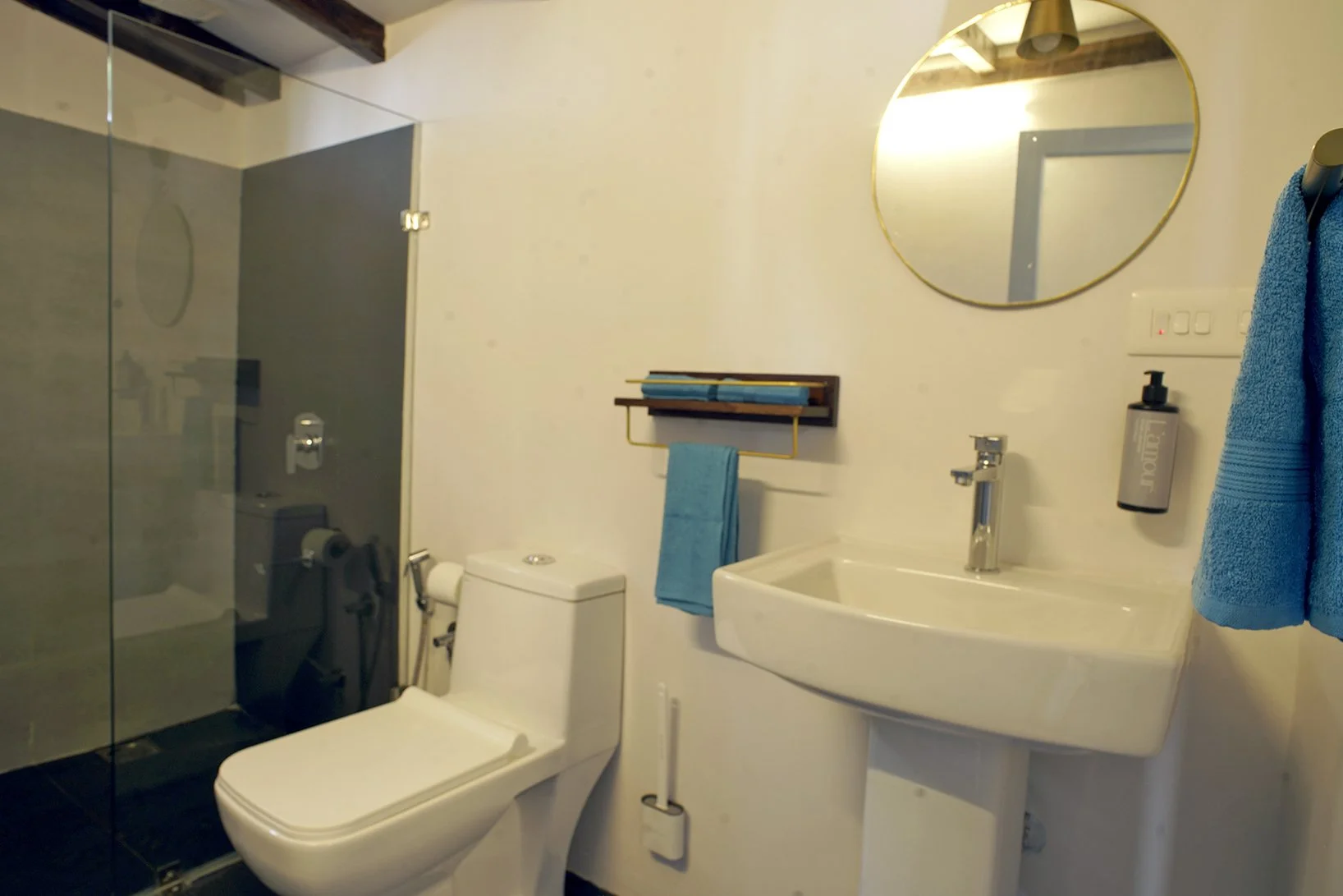 Bathroom with a toilet, white sink, mirror, and blue towels.