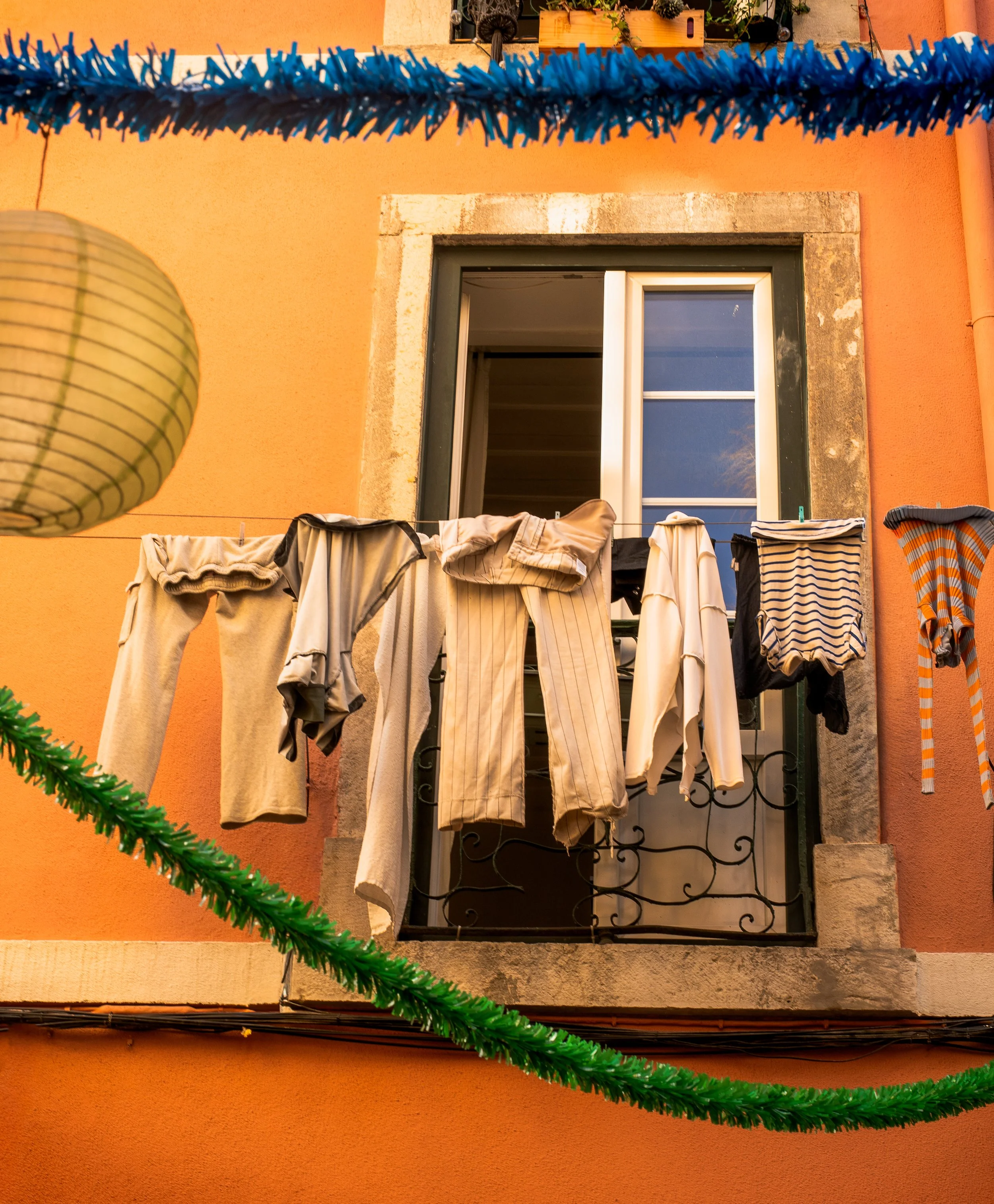 Laundry on clothesline at pink-orange building in Lisbon — symbol of local living and relocation authenticity