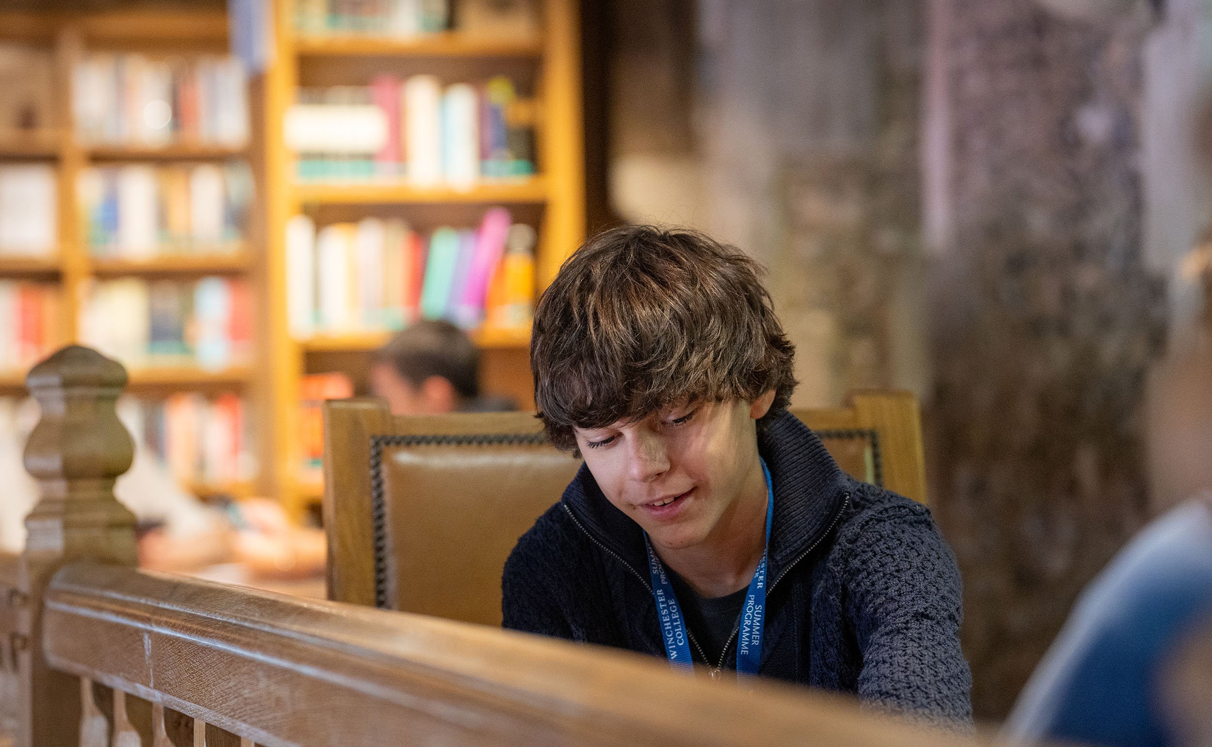 Boy writing at desk at Winchester College summer school