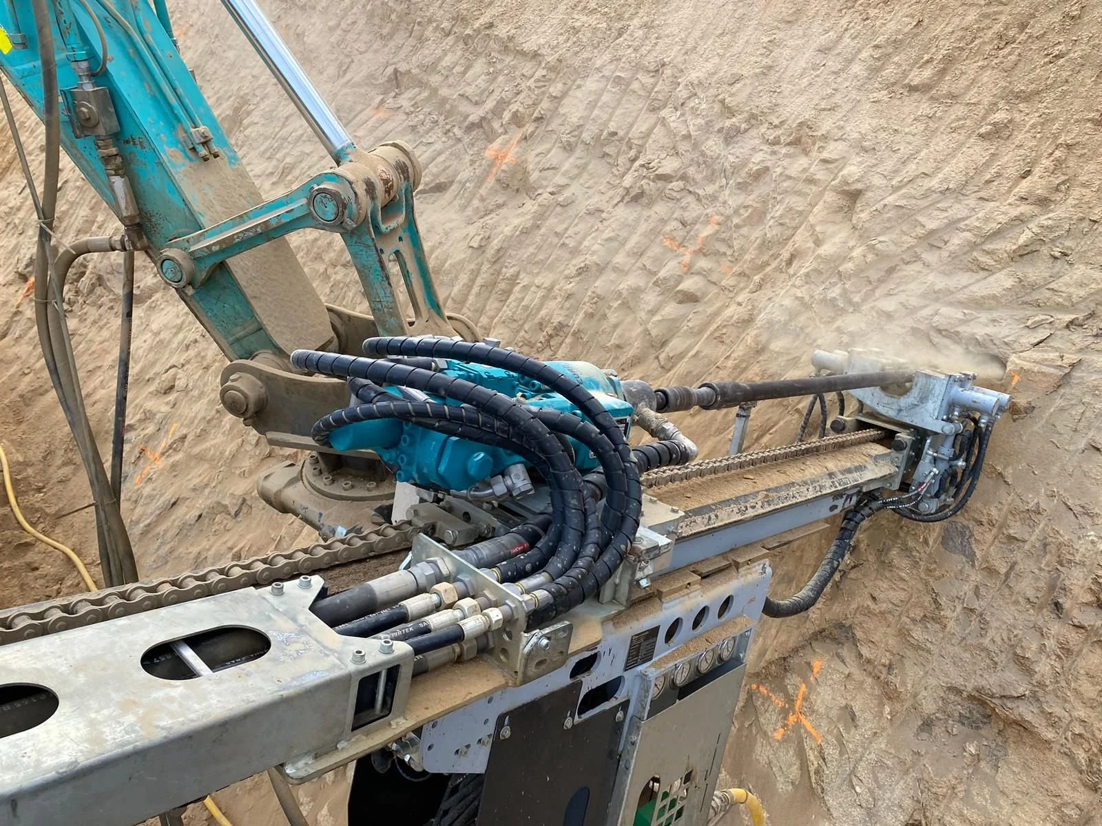 Close-up of a modern tunnel boring machine's cutting head and robotic arm in a sandy excavation site.