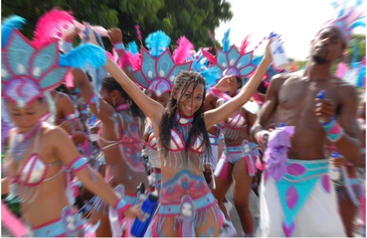 Group of people celebrating in colorful costumes at a festival or parade, showing joy and excitement.