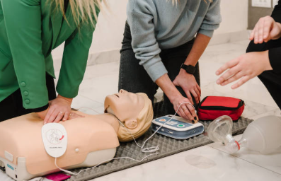 People performing CPR on a training mannequin, practicing with medical equipment.