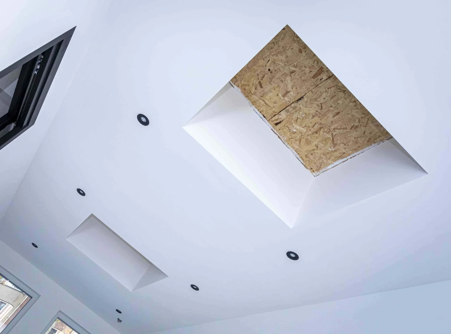 Het plafond van een kamer met inbouwverlichting en een uitsparing die nog afgewerkt moet worden.