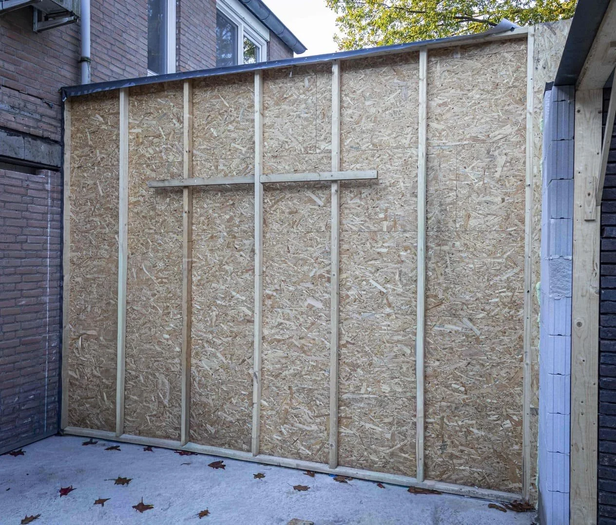 Bouwplaat met houten spanten en OSB-platen, die wordt opgezet aan de buitenkant van een gebouw.