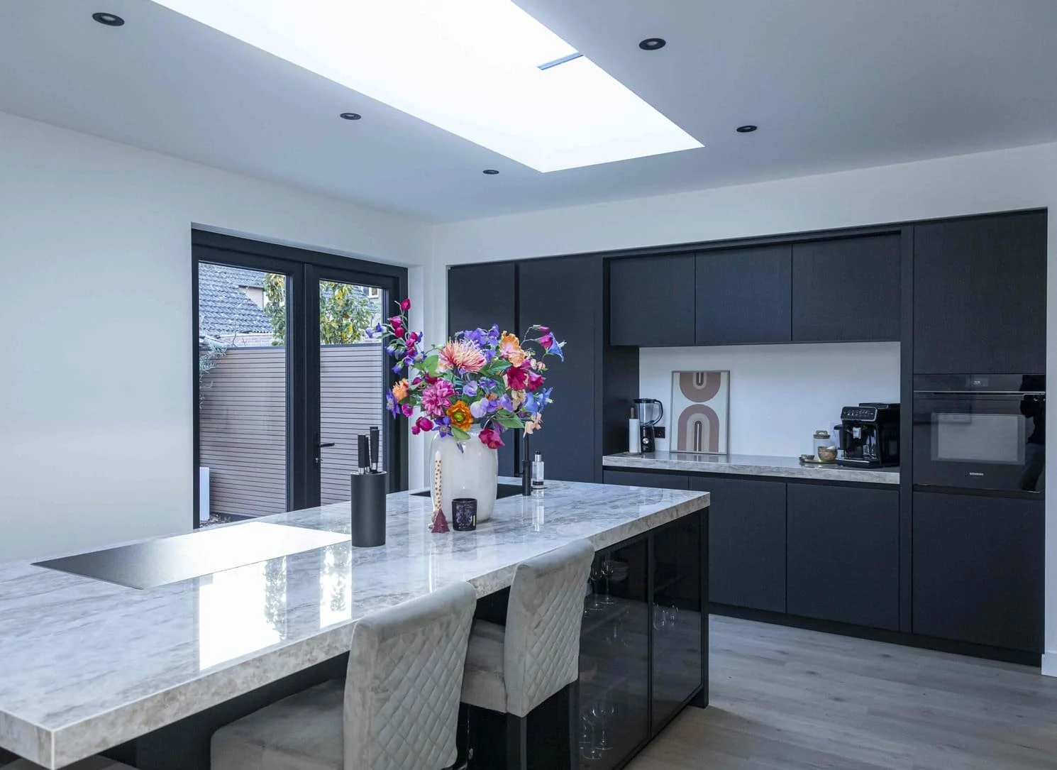 moderne keuken met een eiland, bloemenvaas en ingebouwde apparaten