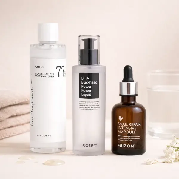 Trois produits de soins de la peau : un tonique clair dans une bouteille transparente, un sérum dans un flacon pompe opaque, une ampoule de réparation à l'extrait d'escargot dans un flacon en verre brun avec pipette.