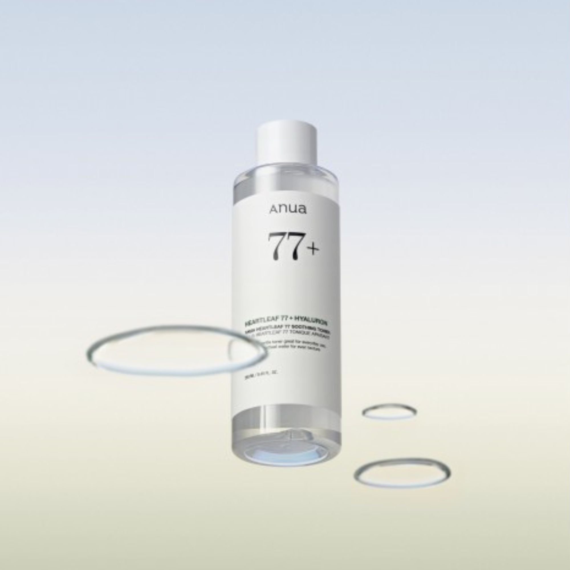 Flacon du Anua Heartleaf 77% + Hyaluron Soothing Toner, entouré d'anneaux d'eau flottants. Tonique K-Beauty hydratant sur fond minimaliste.