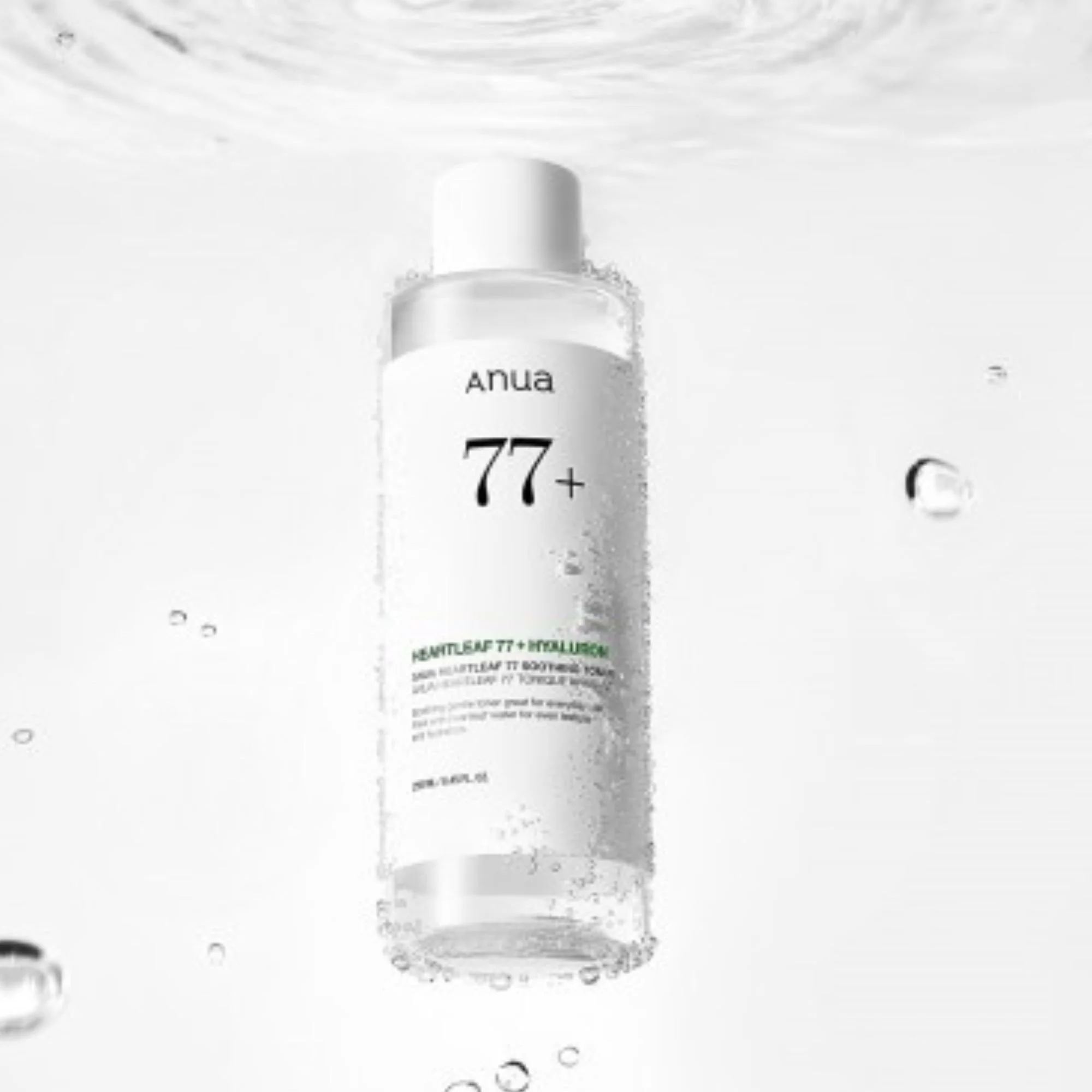 Flacon du Anua Heartleaf 77% + Hyaluron Soothing Toner submergé ou sous l'eau. Tonique K-Beauty hydratant en noir et blanc, avec gouttes et bulles.