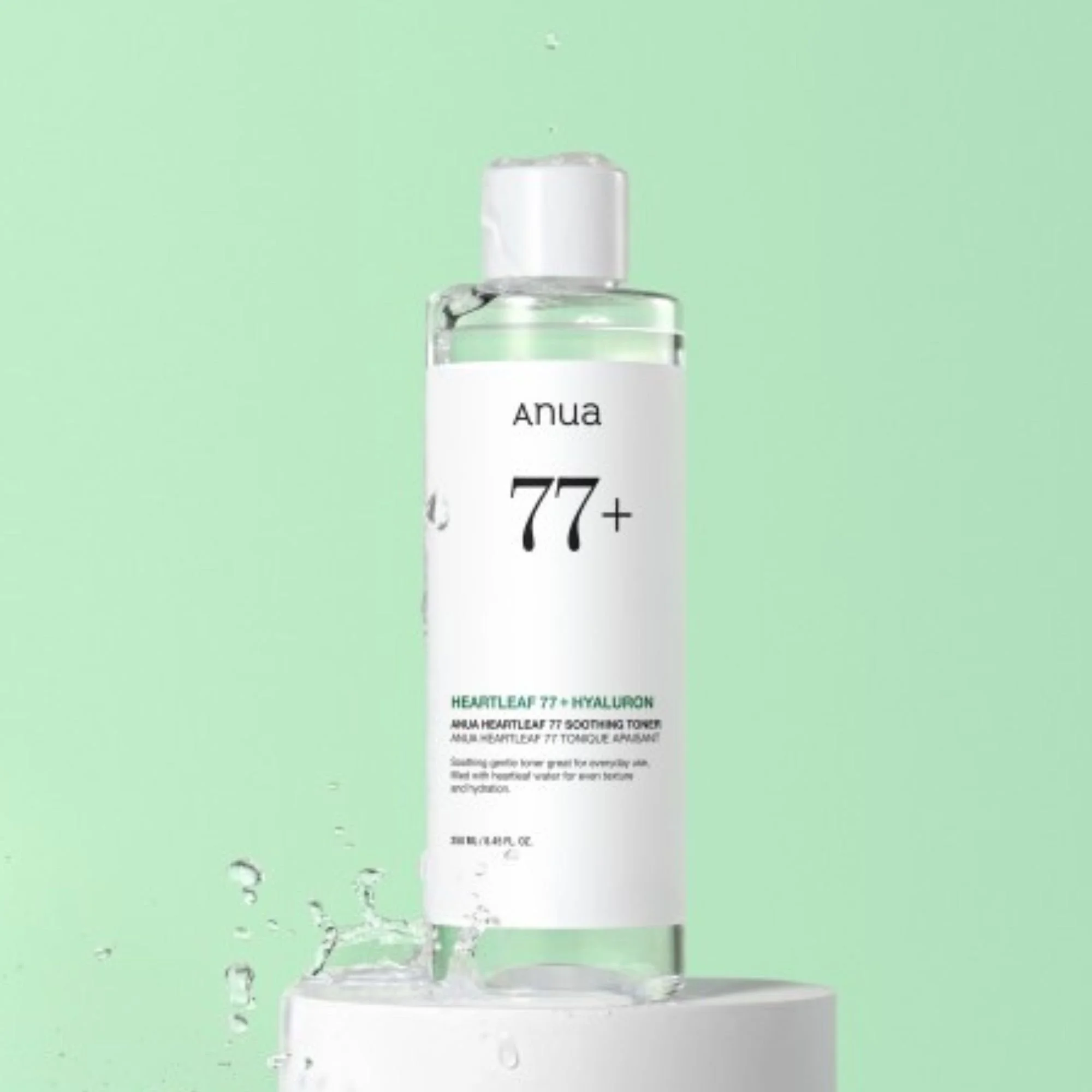 Flacon du Anua Heartleaf 77% + Hyaluron Soothing Toner sur un socle blanc. Tonique K-Beauty rafraîchissant sur fond vert avec éclaboussures d'eau.