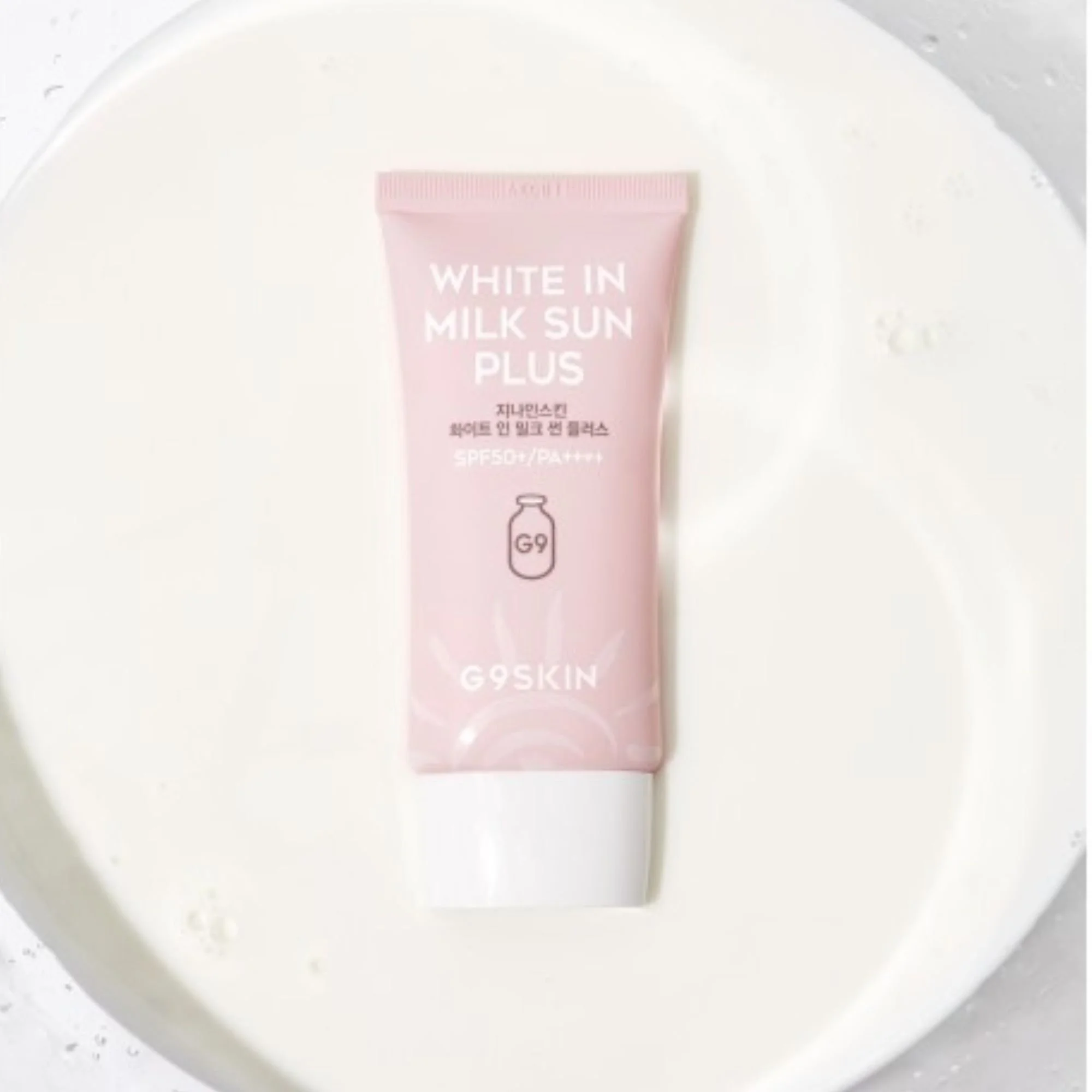 Photo de studio G9SKIN White In Milk Sun Plus dans du lait. Crème solaire K-Beauty SPF50+ PA++++ rose pâle dans un bol de liquide blanc.