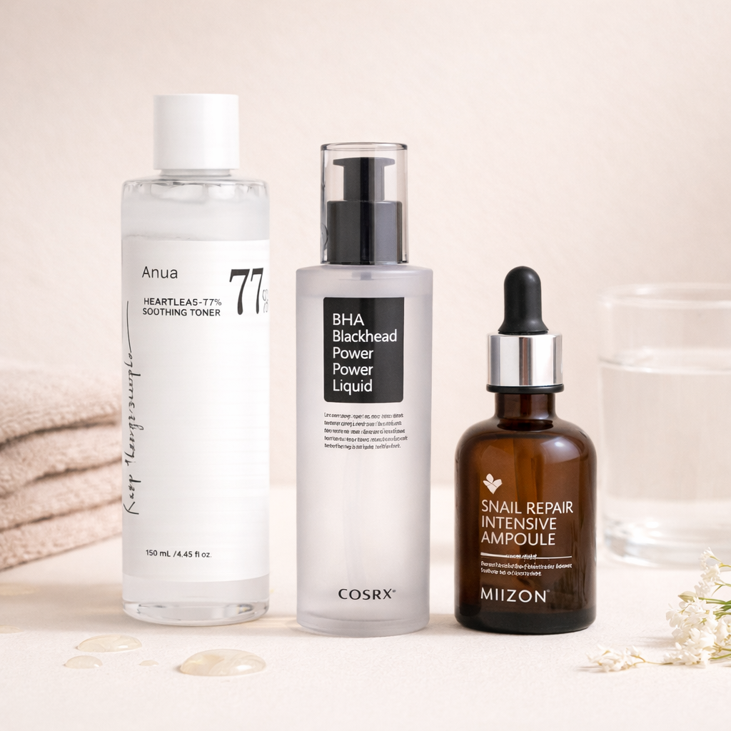 Trois bouteilles de soins de la peau, une serviette beige pliée, un verre d'eau, et quelques fleurs blanches.