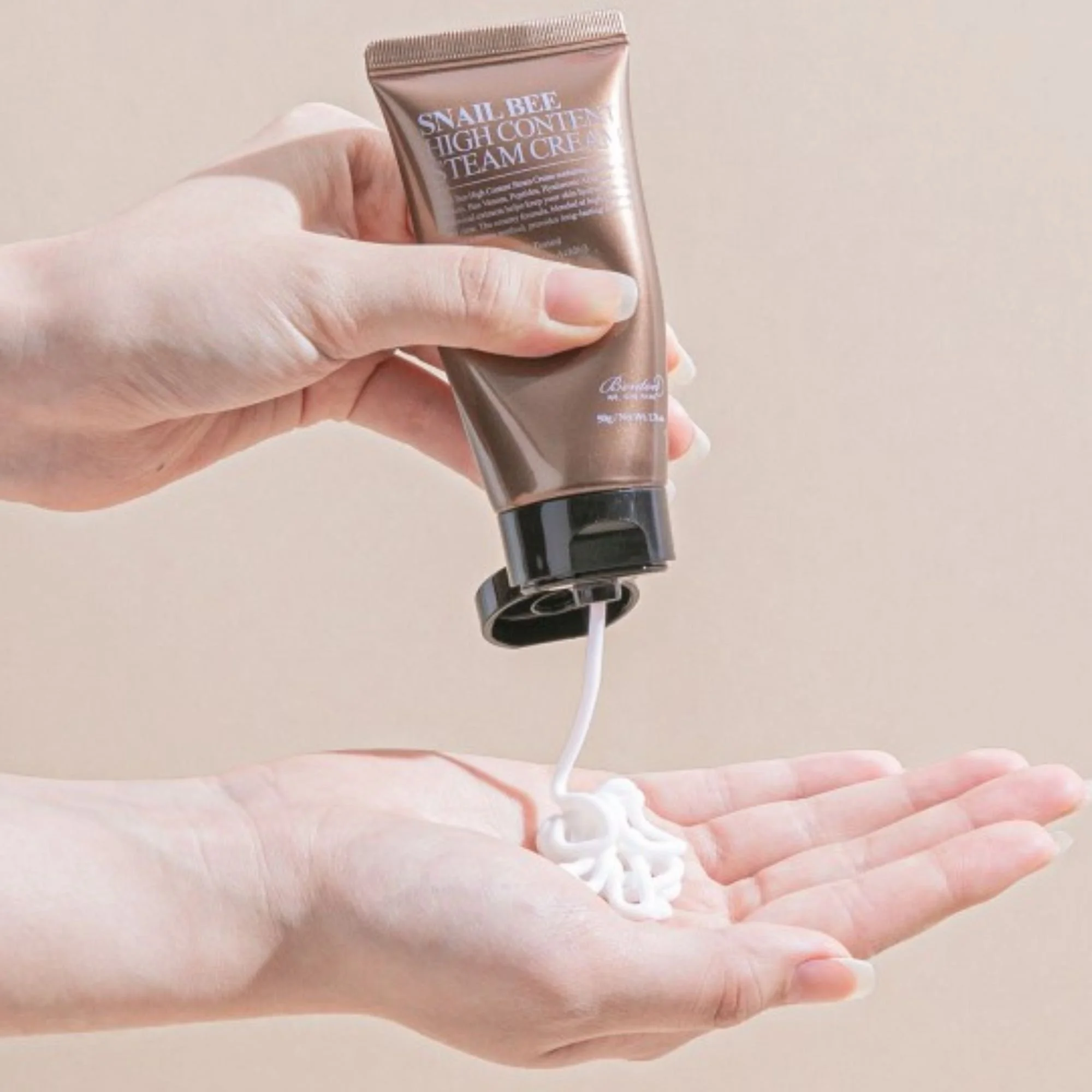 Mains appliquant la BENTON Snail Bee High Content Steam Cream. Texture épaisse de la crème K-Beauty à la bave d'escargot et au venin d'abeille.
