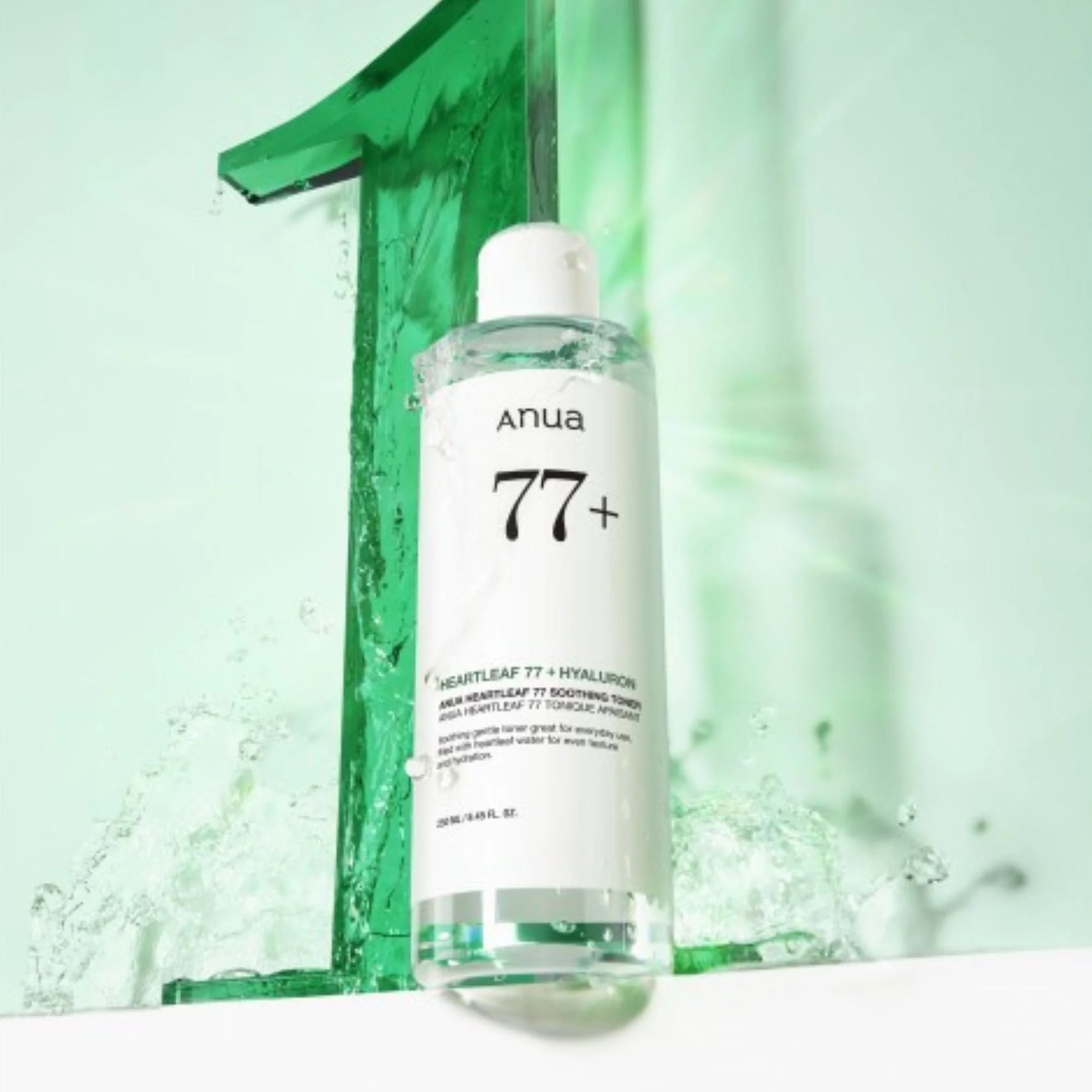 Flacon du Anua Heartleaf 77% + Hyaluron Soothing Toner dans un décor aqua avec éclaboussures d'eau. Tonique K-Beauty apaisant.