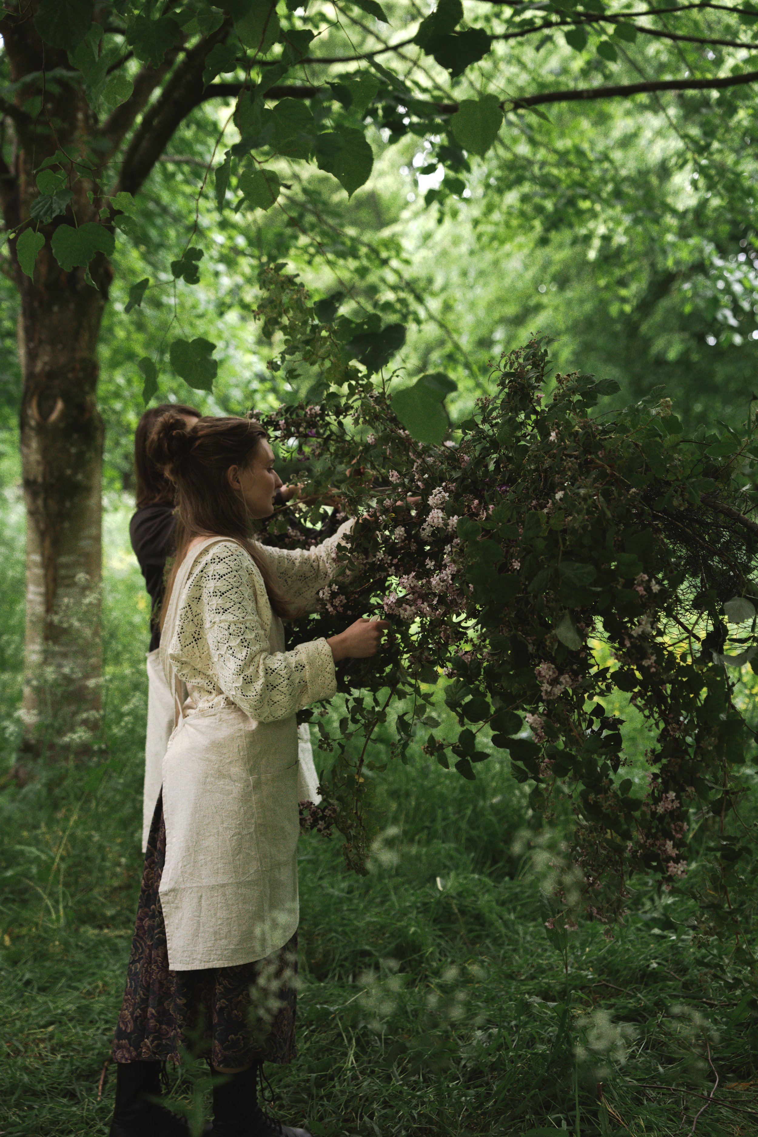 woman arranging flowers into a floating outdoor floral cloud installation