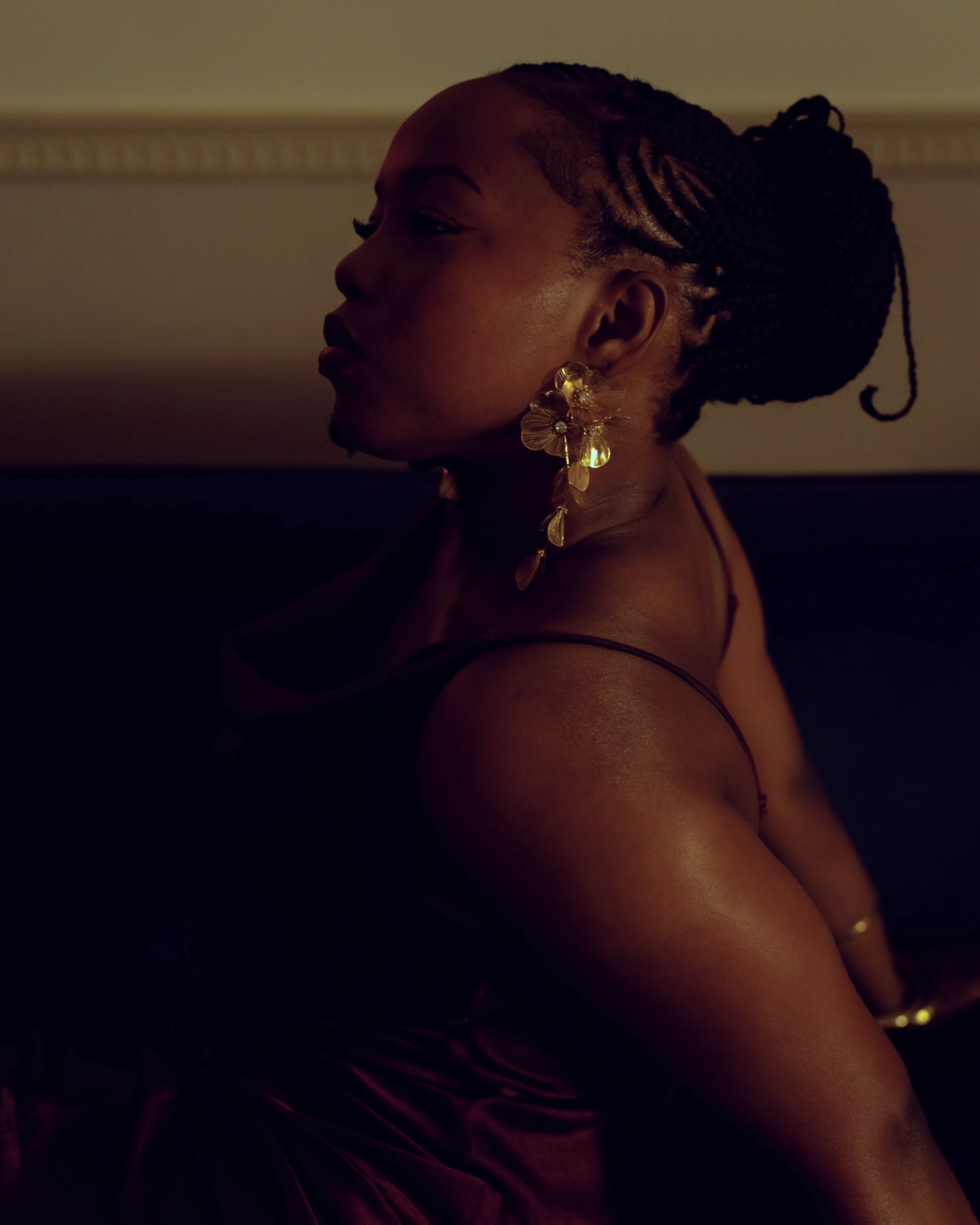 Cinematic close-up of a woman with braided hair and gold earrings, using low-key lighting and soft shadow falloff to shape depth and tone — signature portrait cinematography by ABHIOLAR.ART.