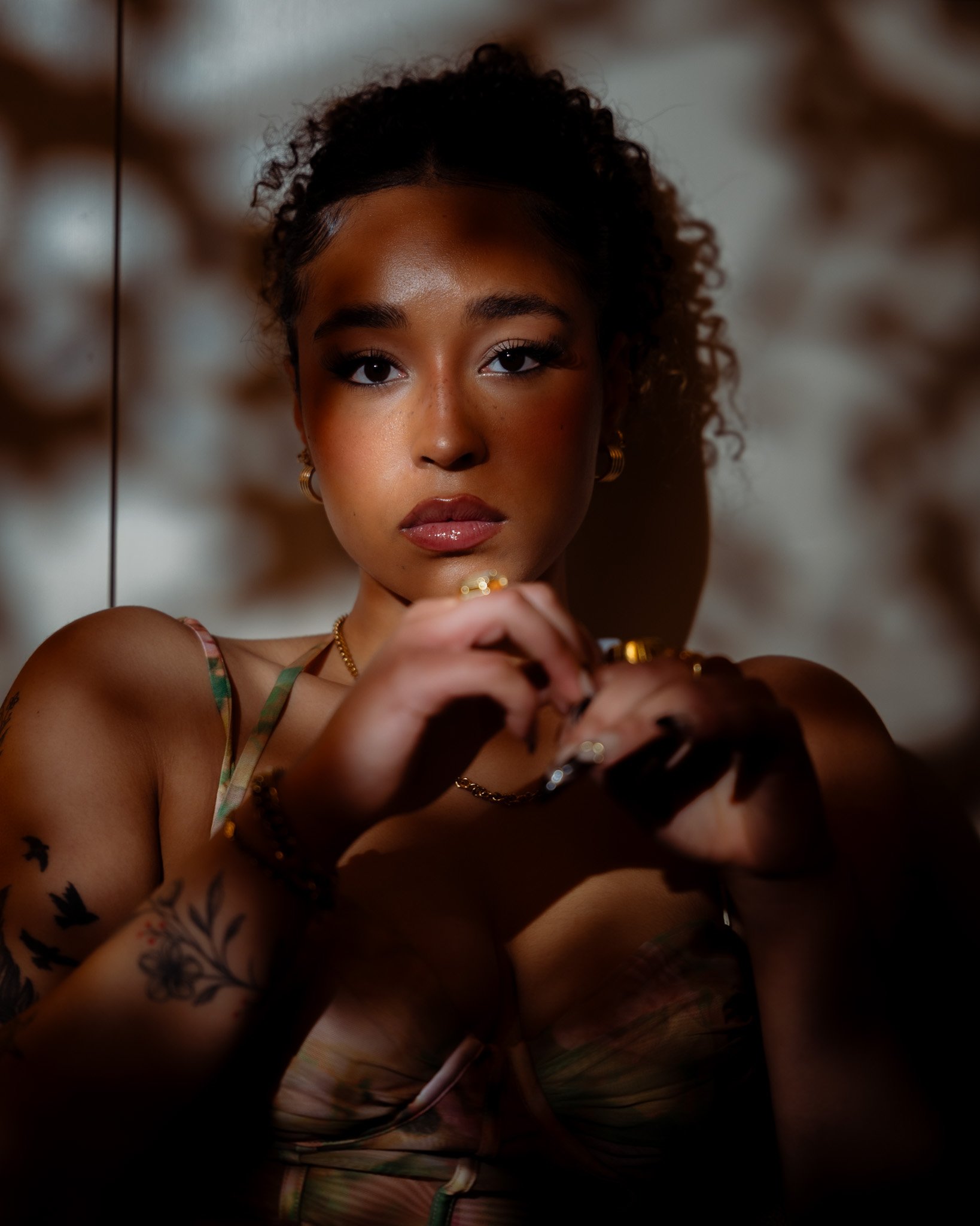 Cinematic close-up of a woman with curly hair and jewellery, using soft directional light and reflective surfaces to shape depth and tone — portrait cinematography by ABHIOLAR.ART.
