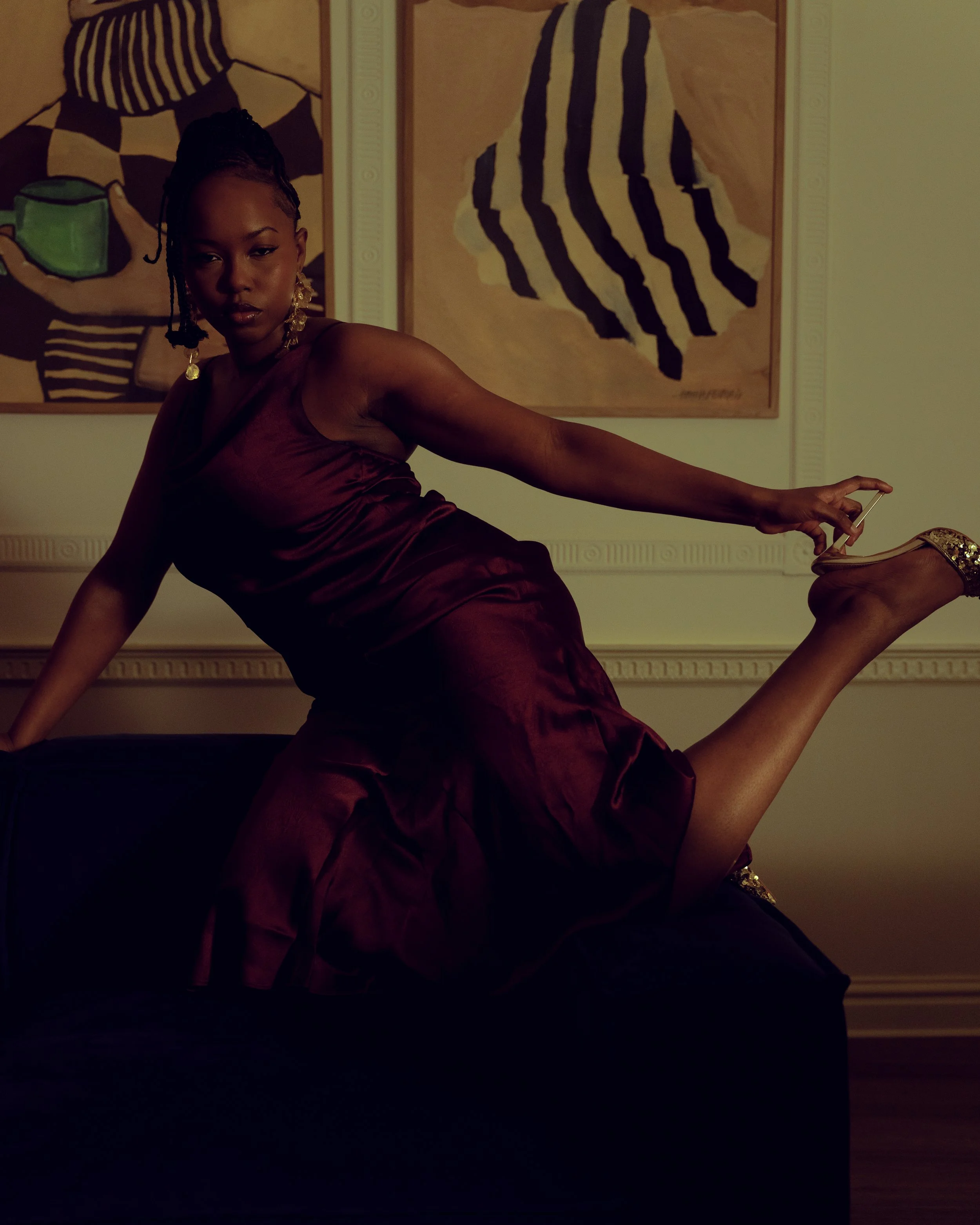 Cinematic portrait of a woman posed on a sofa, using rich colour contrast, interior composition and soft ambient light to create depth and mood — signature cinematography by ABHIOLAR.ART.