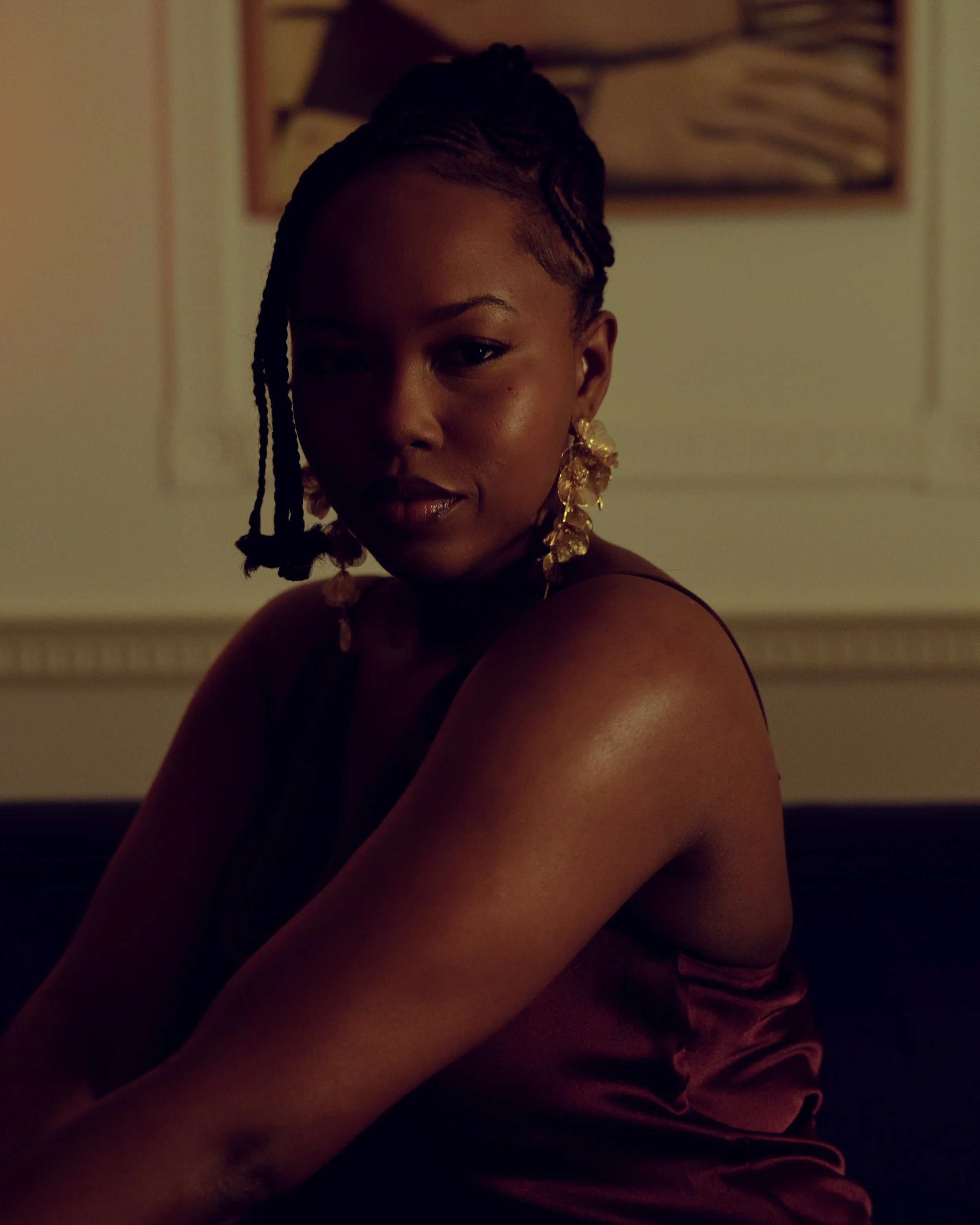 Cinematic close-up of a woman with braided hair and gold earrings, using warm directional light and soft shadow to shape depth and tone — signature portrait cinematography by ABHIOLAR.ART.