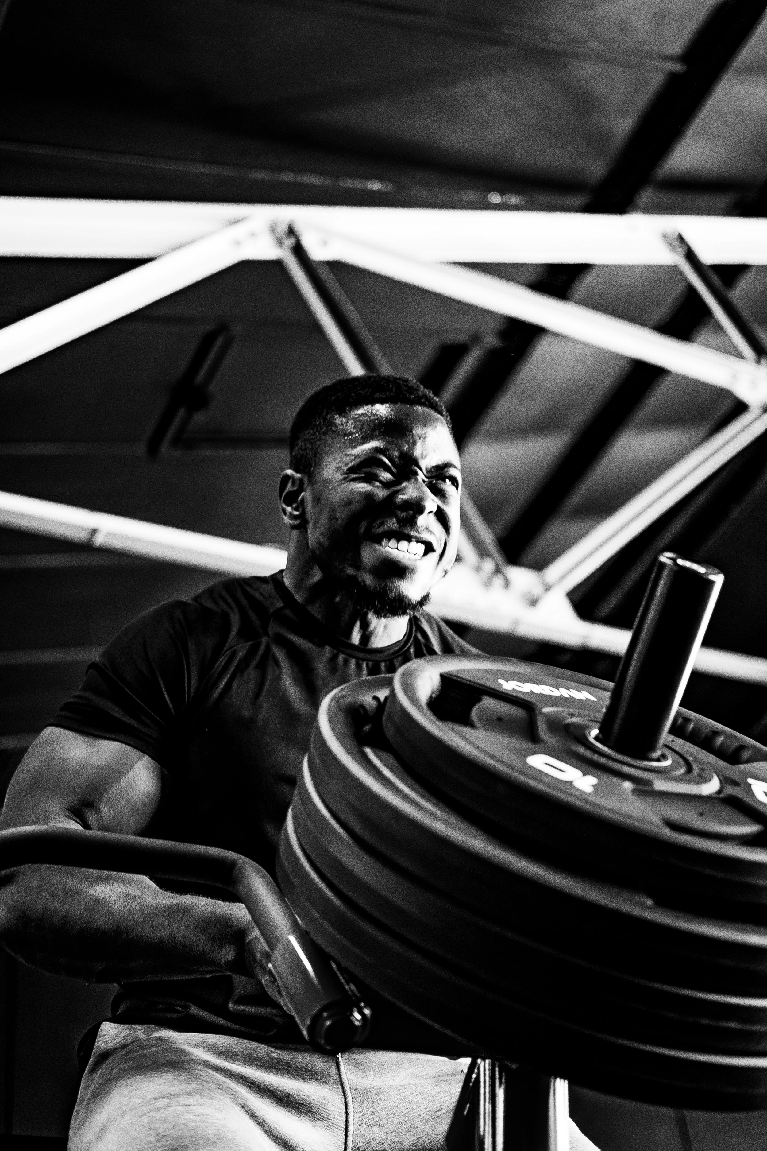 A man angrily lifting a weight in a gym, with a defeated facial expression.