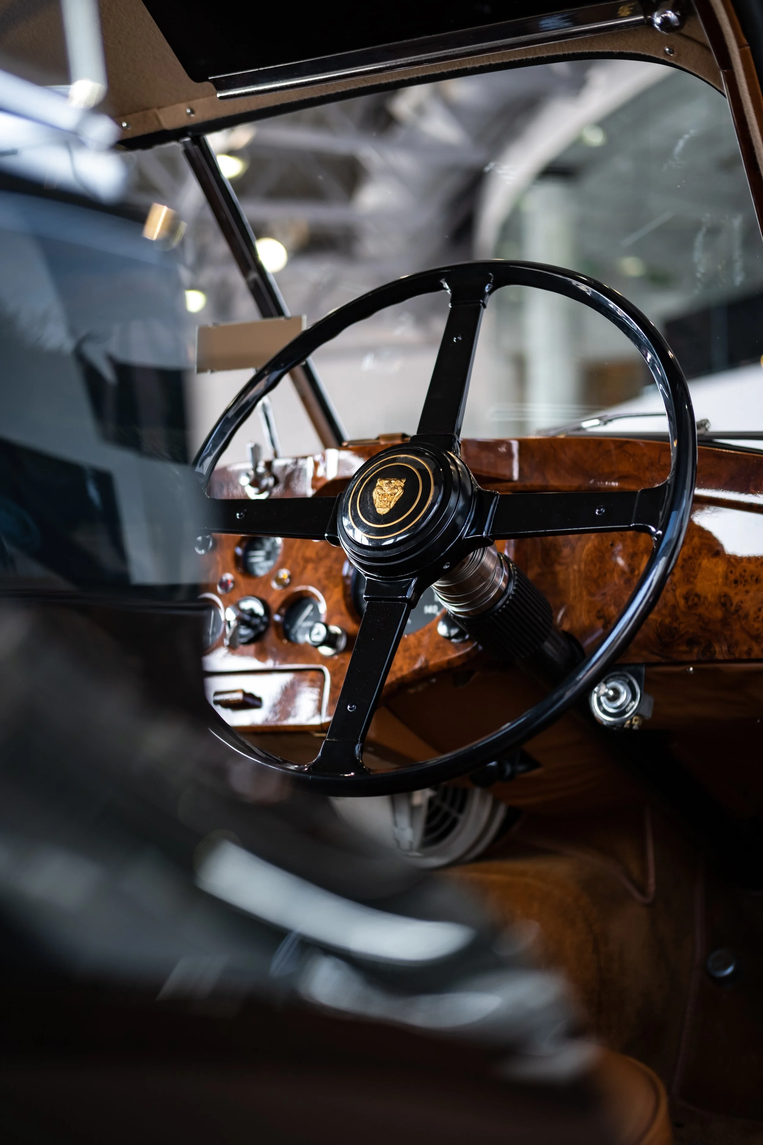 Interior view of a vintage car steering wheel and dashboard with wood accents.