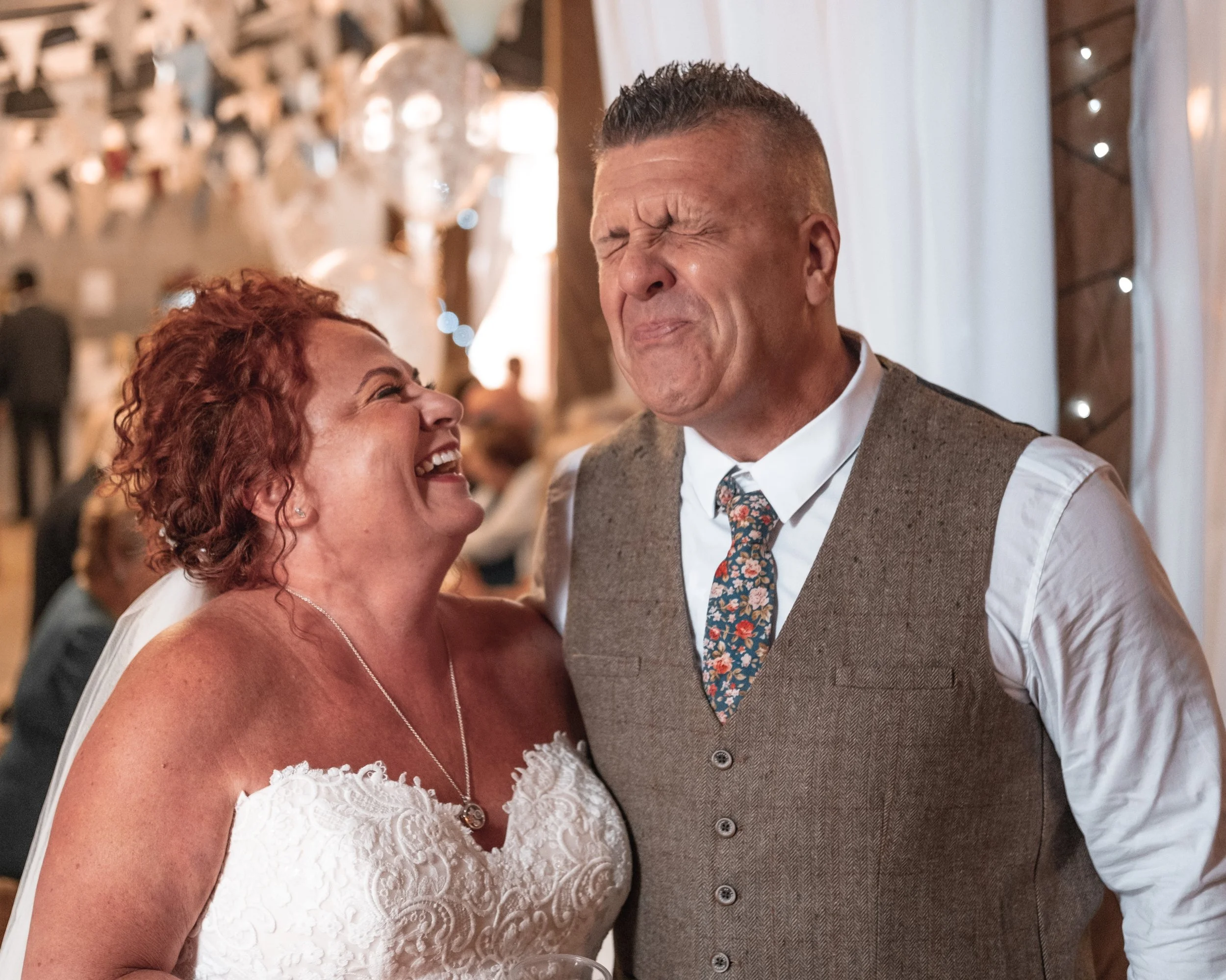 A bride and groom sharing a joyful and emotional moment at their wedding reception, smiling and laughing.