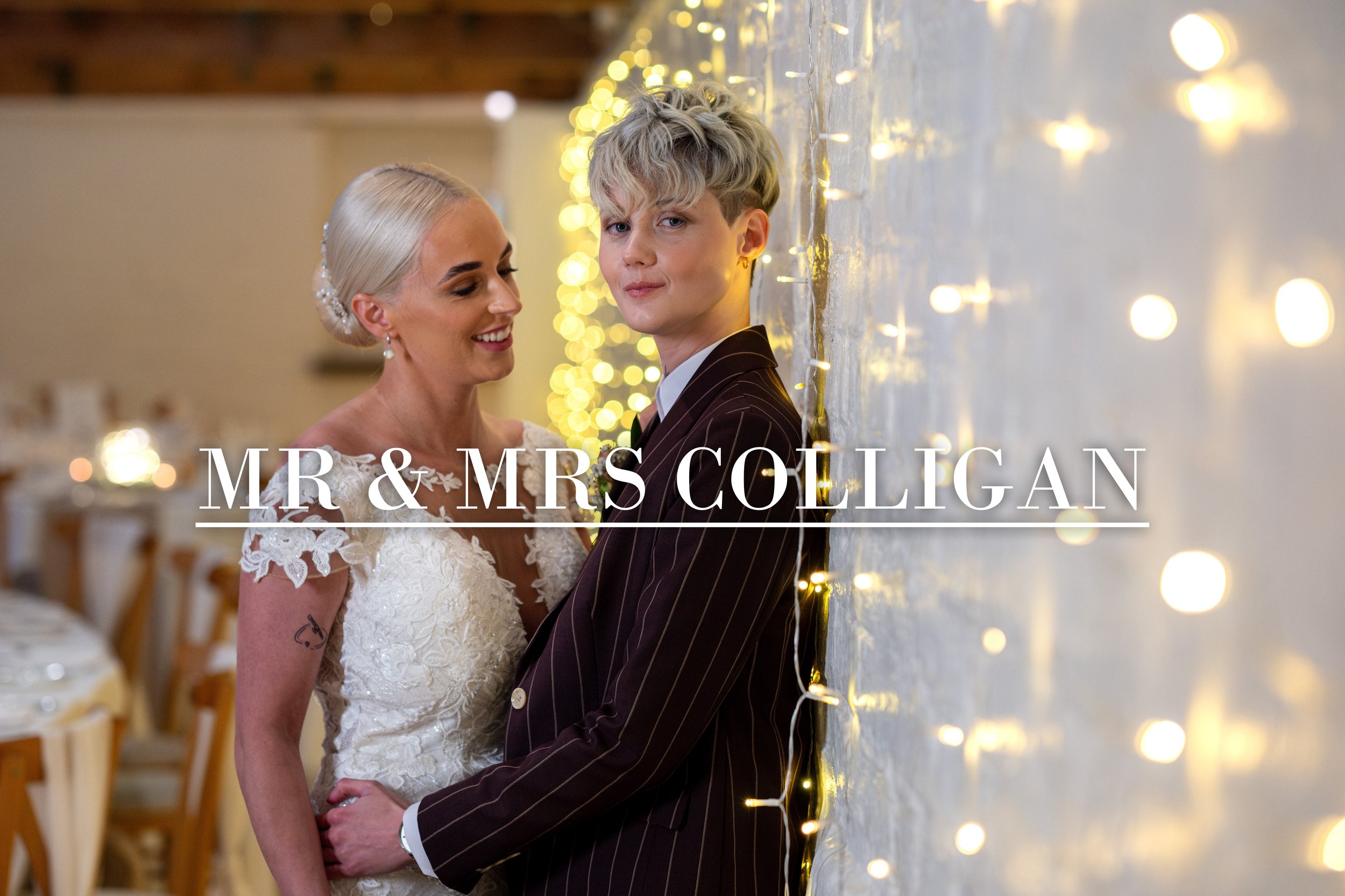 A bride and groom standing close together at their wedding reception, smiling and looking happy. The bride has platinum blonde hair styled in an elegant updo, wearing a lace wedding dress, and the groom has light blonde hair, wearing a dark pinstripe