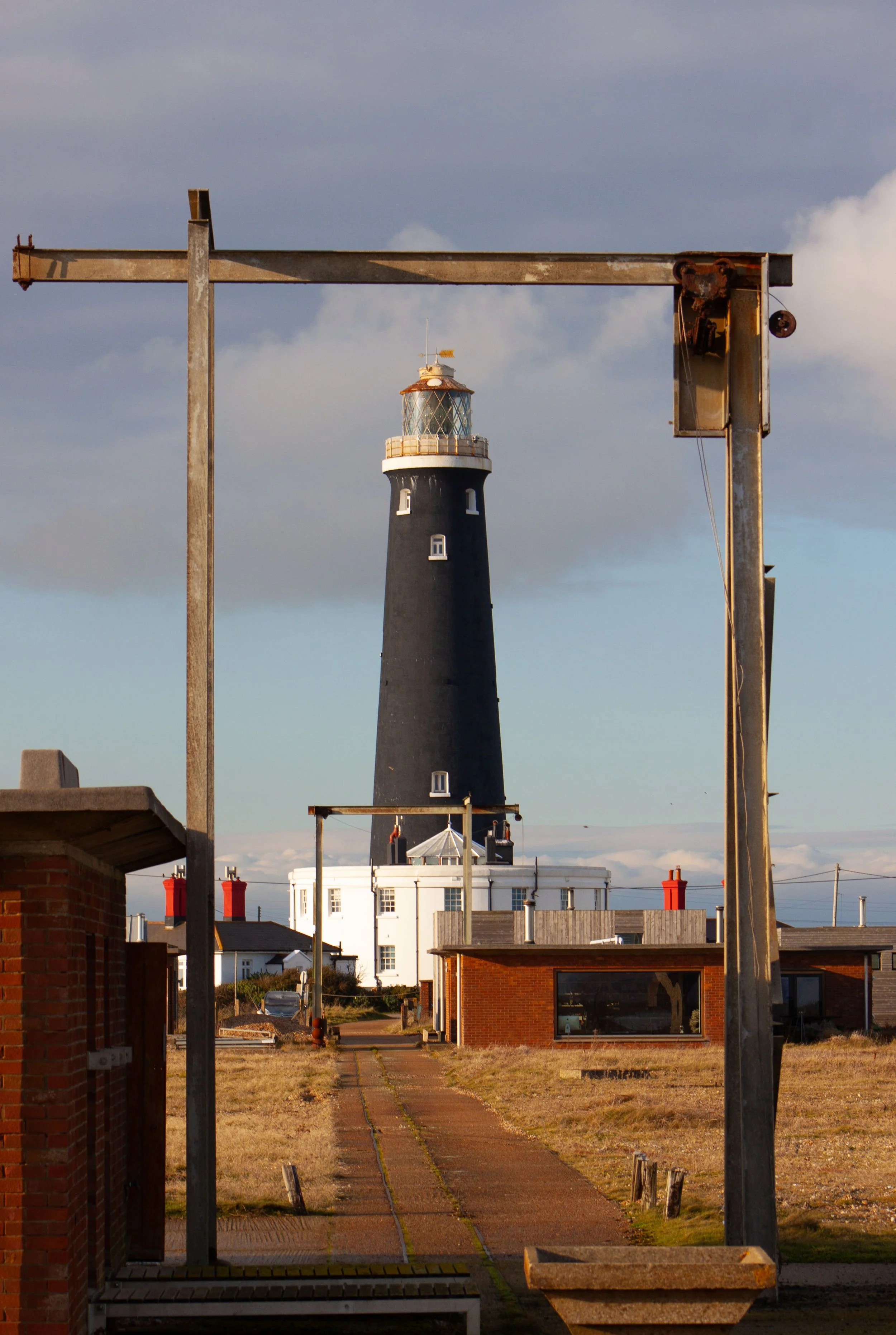 Old Lighthouse at Dungeness framed in a disused gantry