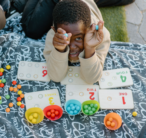 Young boy playing a card game with colorful counters on a bed.