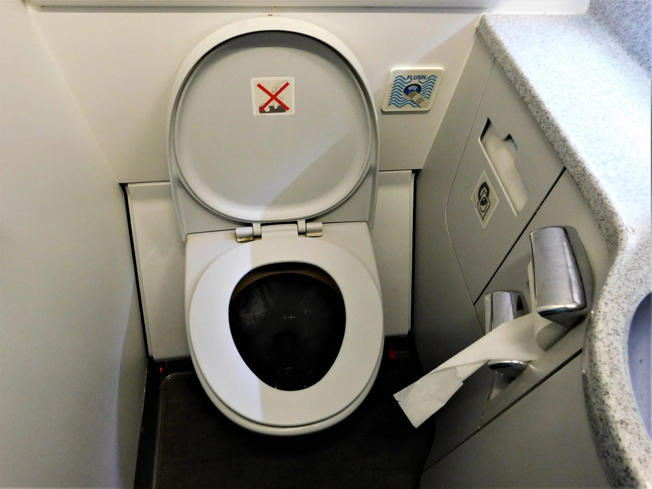 Airplane toilet, tissue paper, and a countertop.