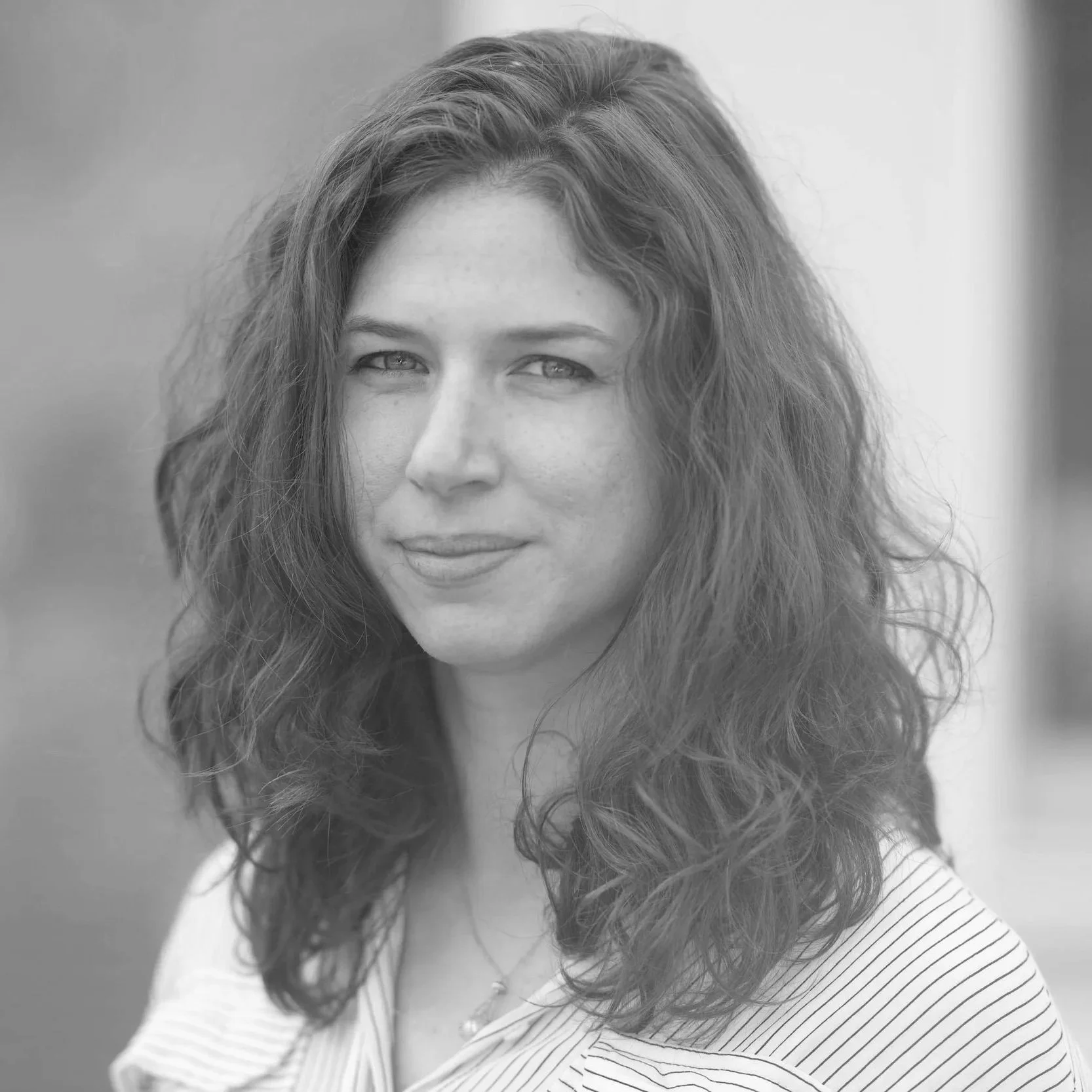 Black and white portrait of a woman with wavy hair, looking at the camera with a slight smile.