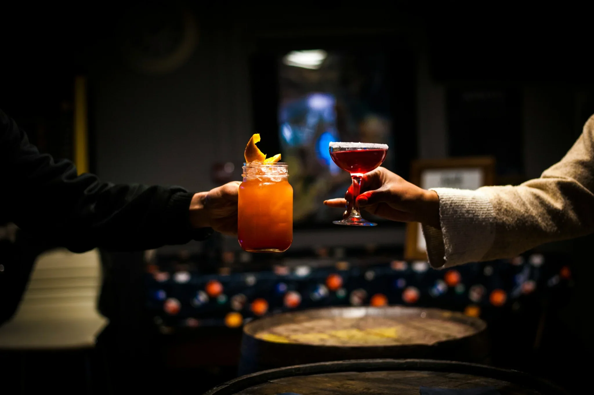 Zwei Personen halten unterschiedliche Cocktails an einer Bar – Motiv zum Vergleich zwischen Direktbuchung und Eventagentur für Cocktailkurse in Hamburg.