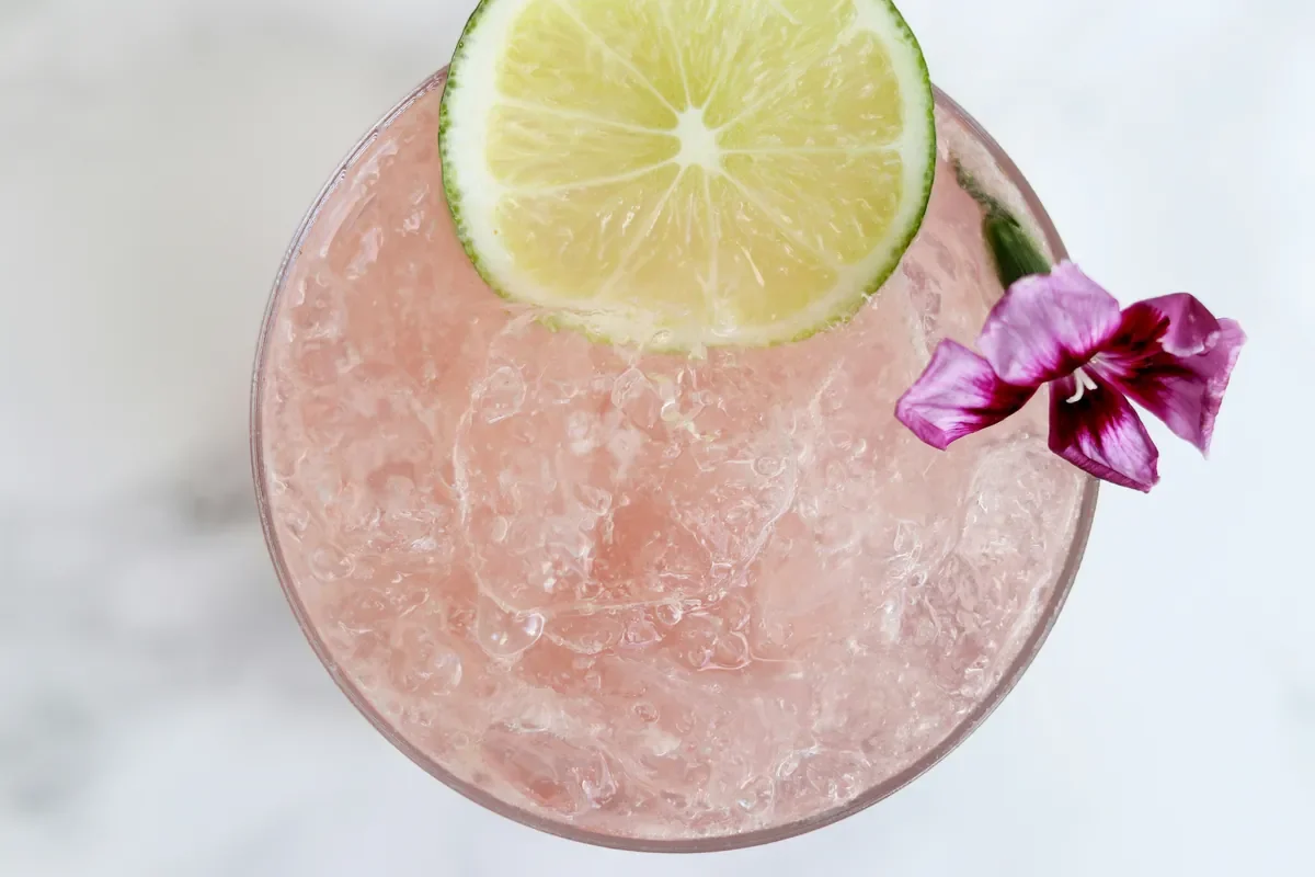Rosa Cocktail mit Crushed Ice, Limettenscheibe und Blüte beim Cocktailkurs in Hamburg von Cocktail Circle.