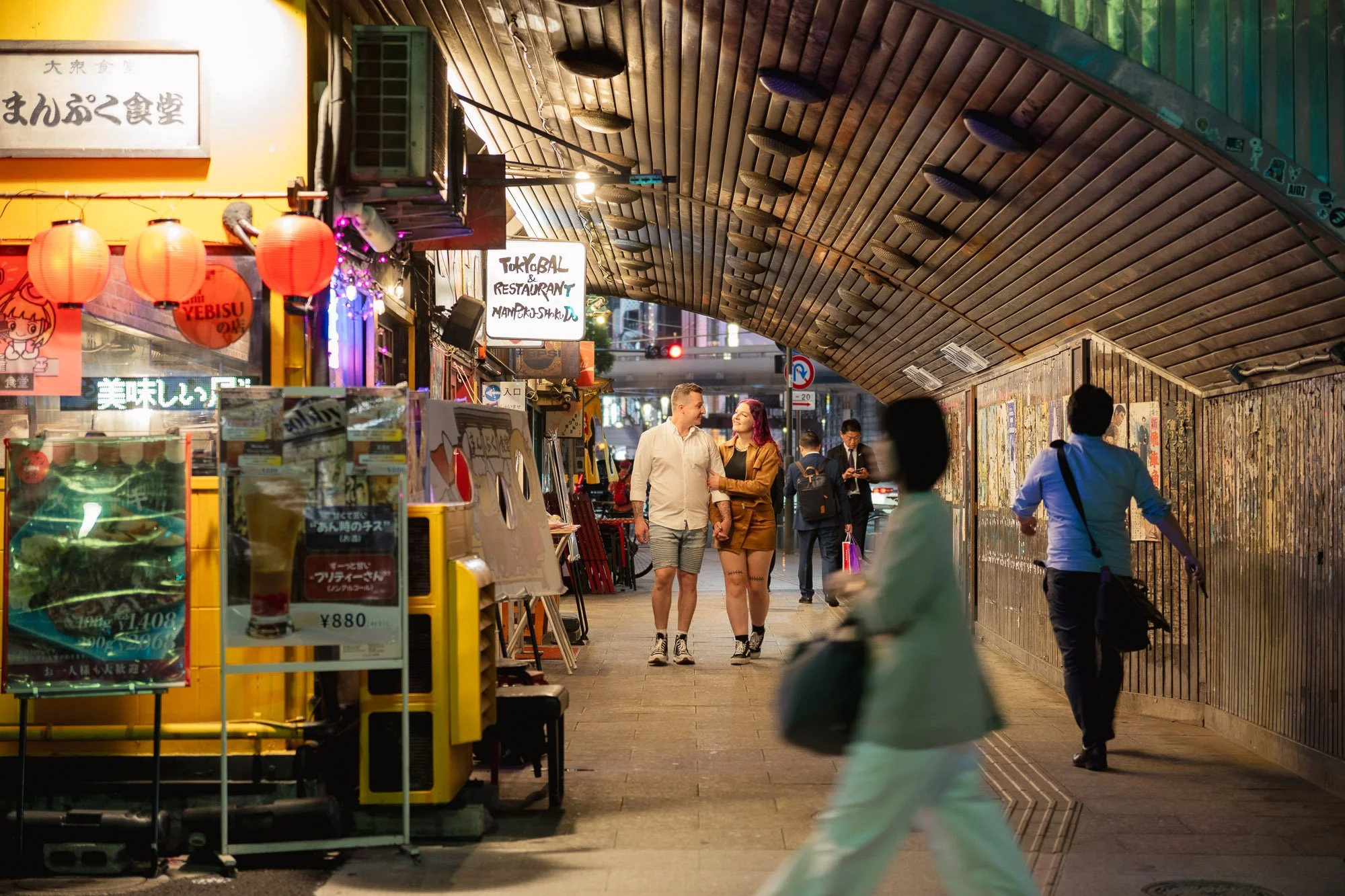 A young couple strolls through a lantern alley in Tokyo.
