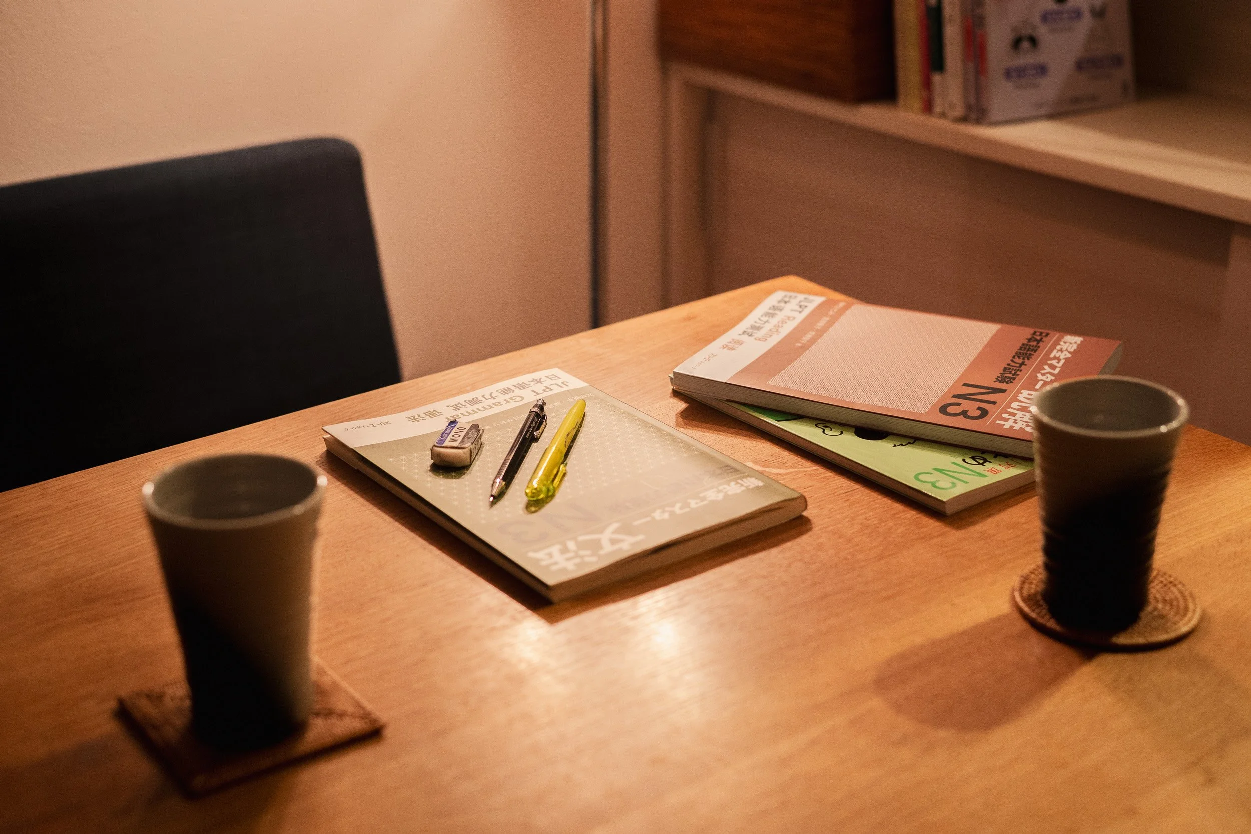 Japanese textbooks spread across a table beside two cups of Japanese tea.