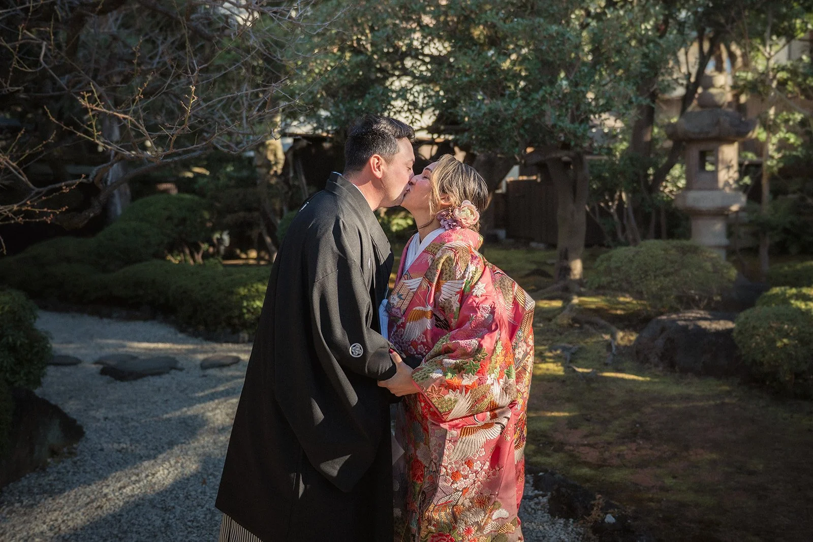 Couple wearing kimonos kiss in a beautiful Japanese garden following a romantic vow renewal ceremony in Tokyo.