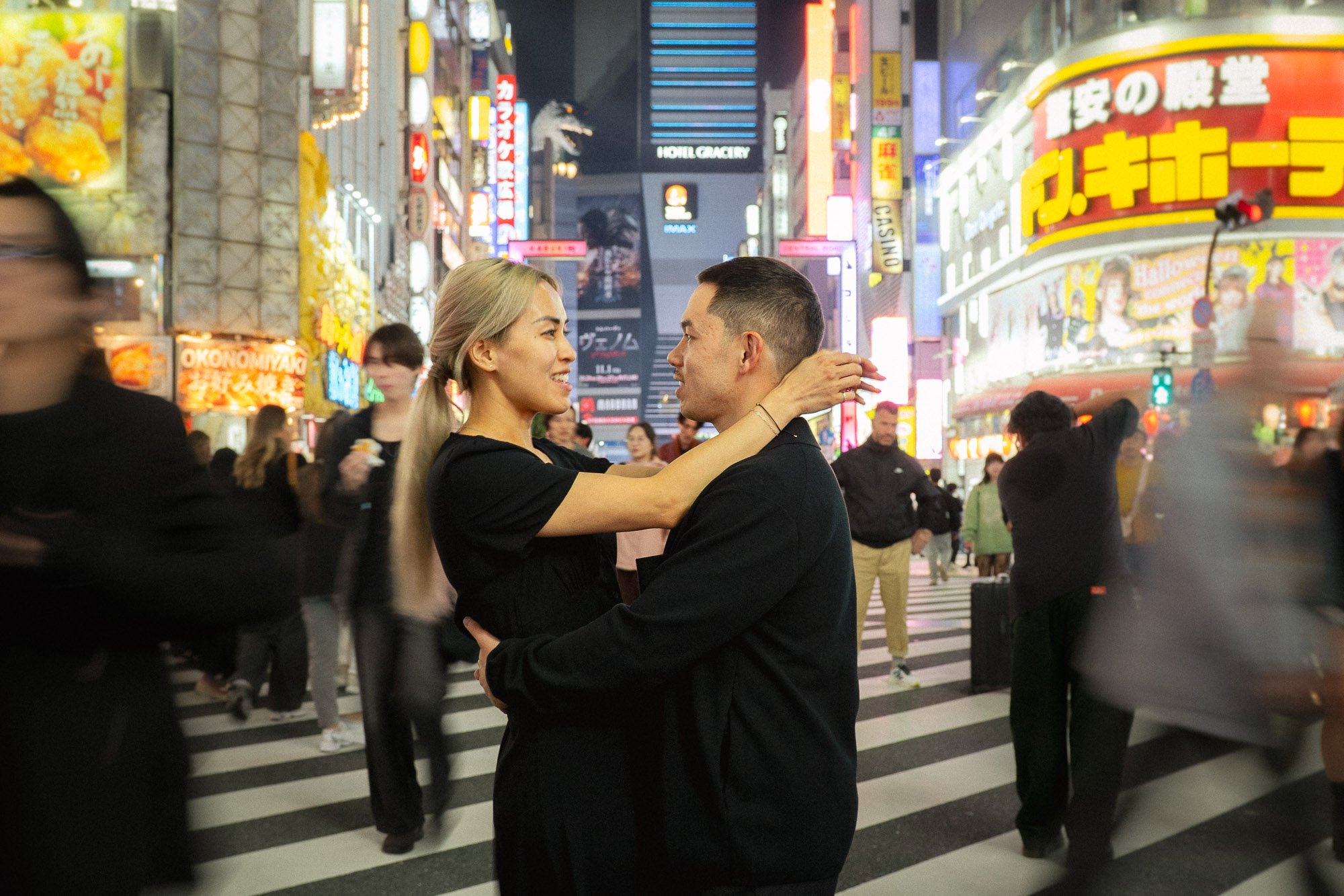 A couple standing together amongst the Tokyo crowds during a nighttime photoshoot in Shinjuku