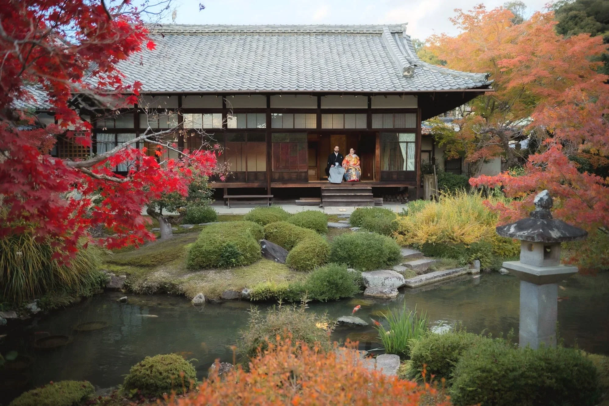 A couple just married and wearing wedding kimonos enjoy a moment overlooking a beautiful private Japanese garden.