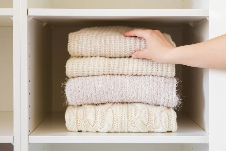 Professionally organized wardrobe with folded sweaters in a Boston home
