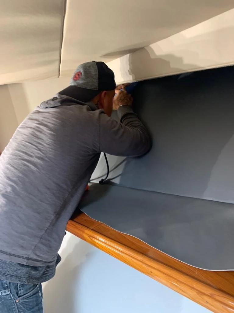 Man repairing or inspecting the underside of a boat in a garage or workshop.