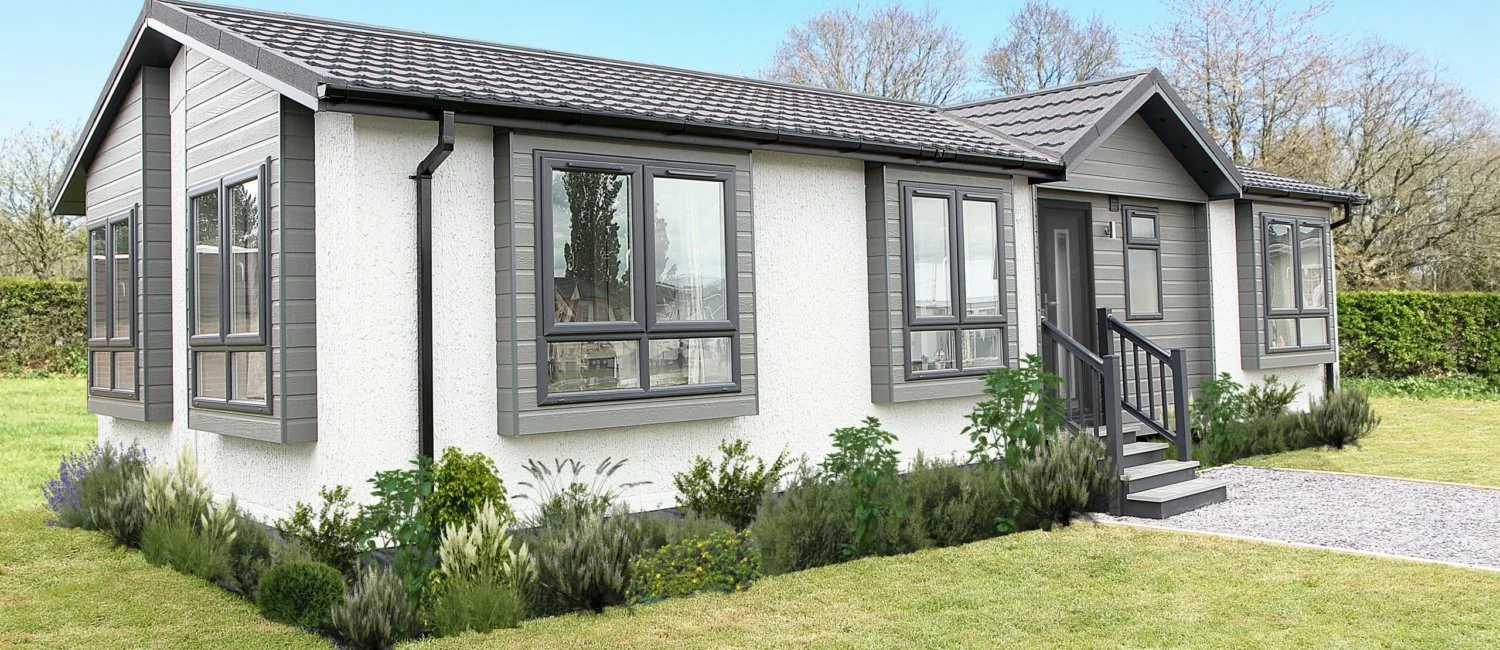 A modern, single-story house with gray siding, multiple windows, and a small front porch with stairs, surrounded by a well-maintained lawn and landscaping.
