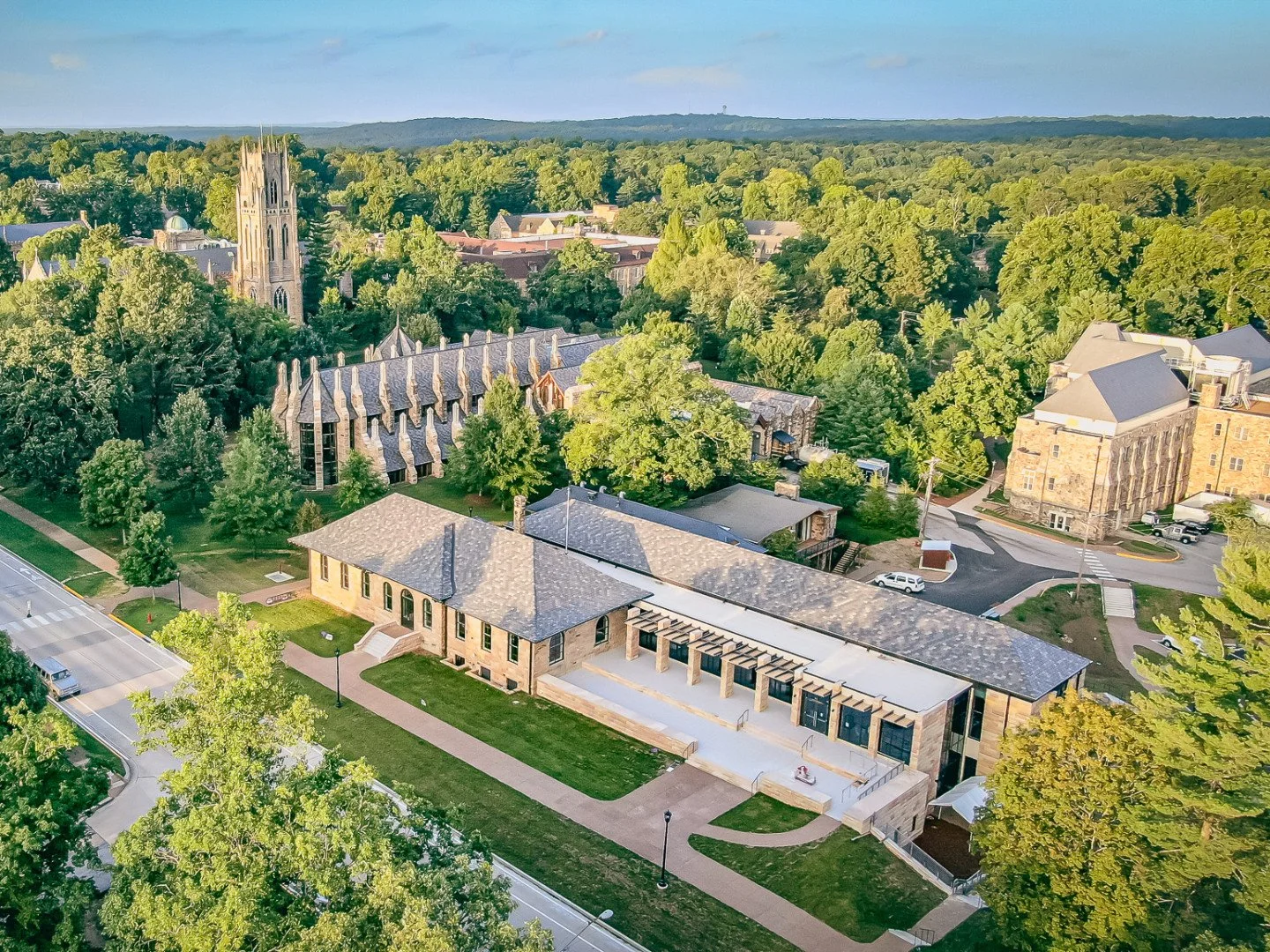 Aerial view of a college campus with historical and modern buildings surrounded by green trees and streets.