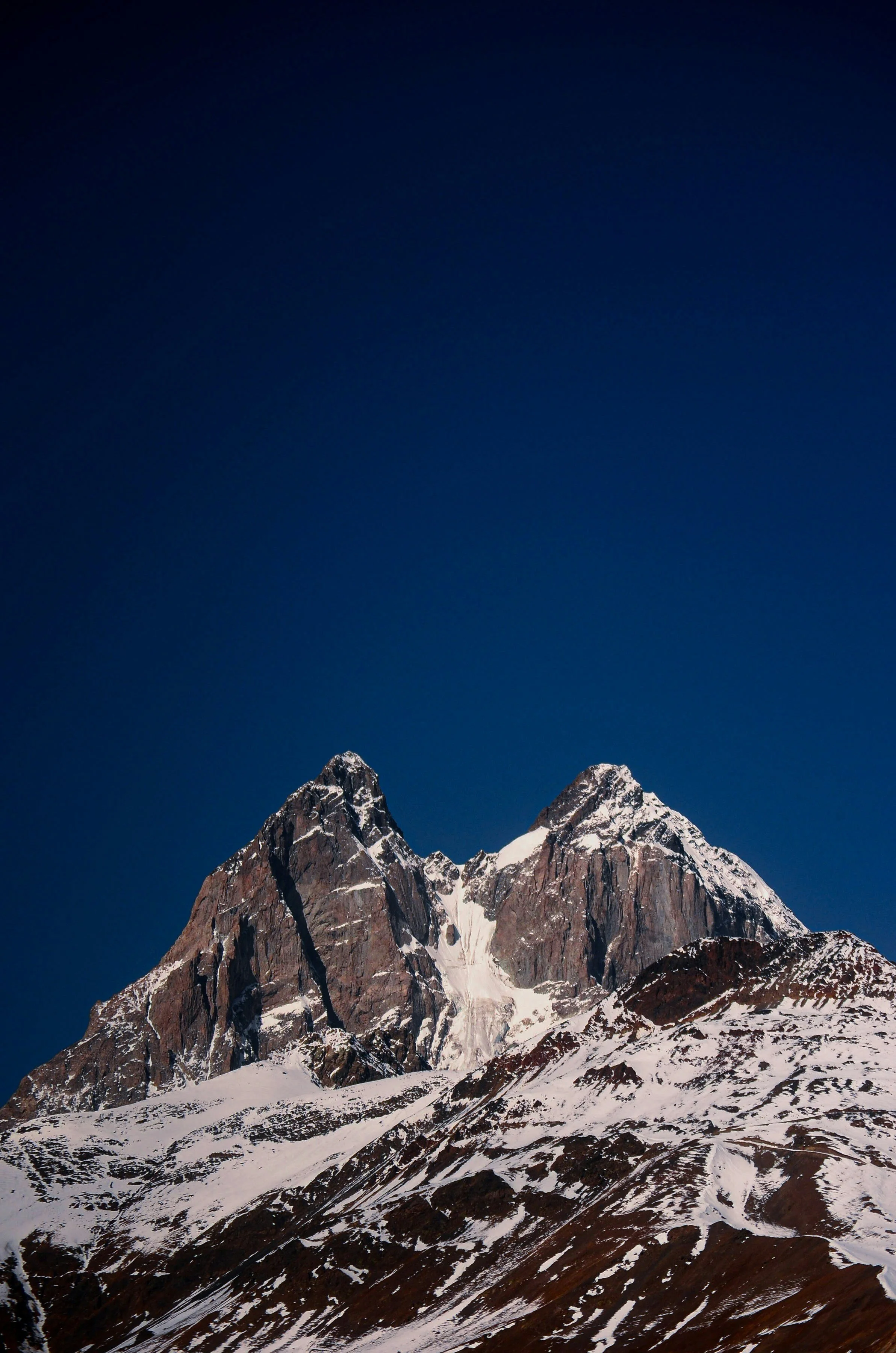 Snow-capped mountain peaks against a dark blue sky.
