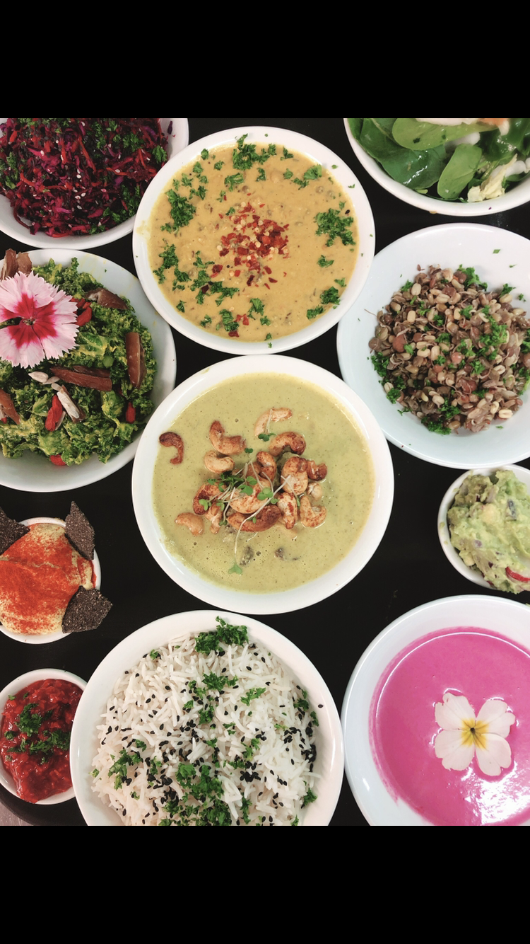Assorted dishes including salads, soups, rice, and dips served in white bowls on a black table.