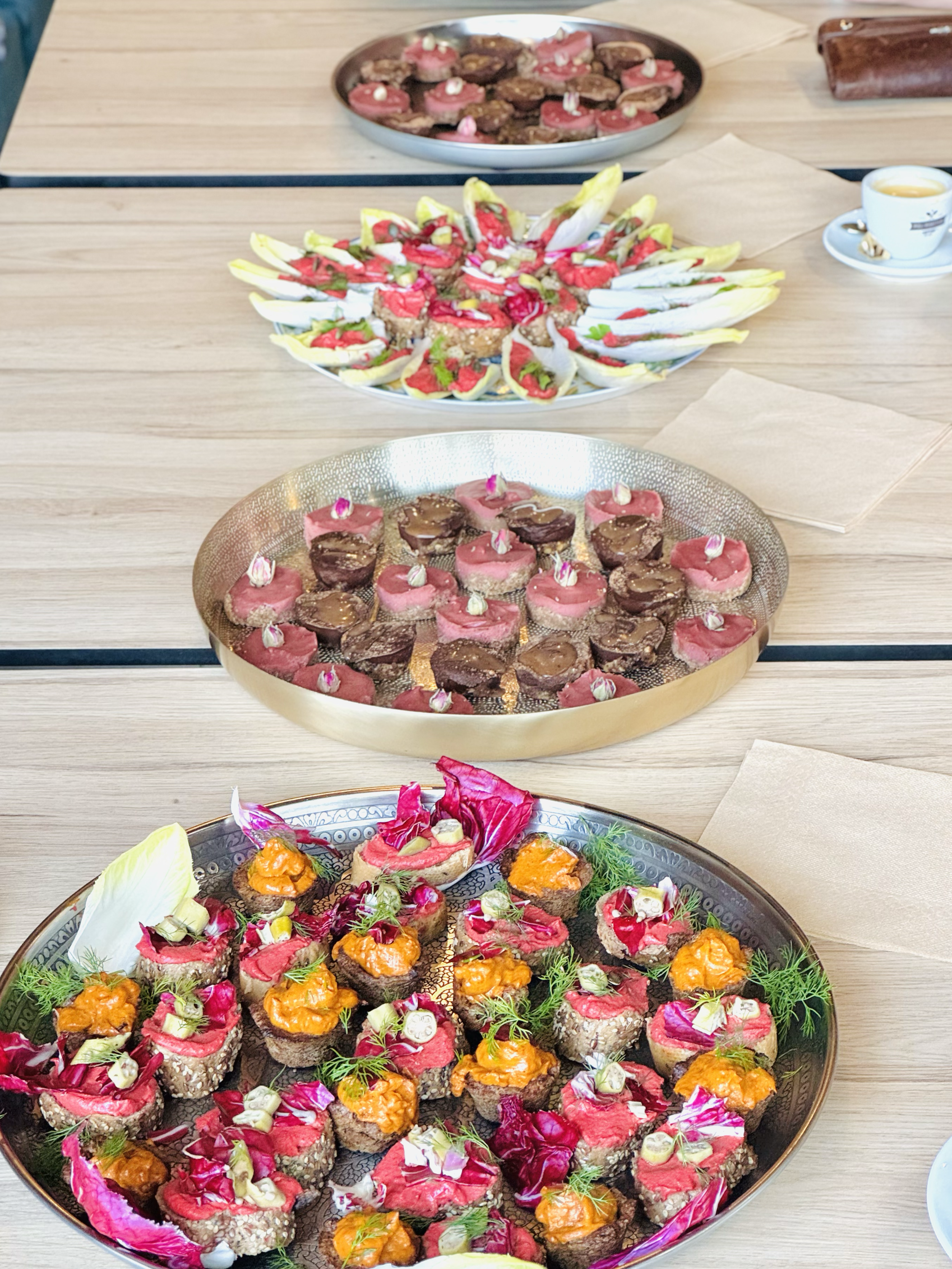 Platters of assorted appetizers, with a wooden table, cups of tea, and napkins in the background.