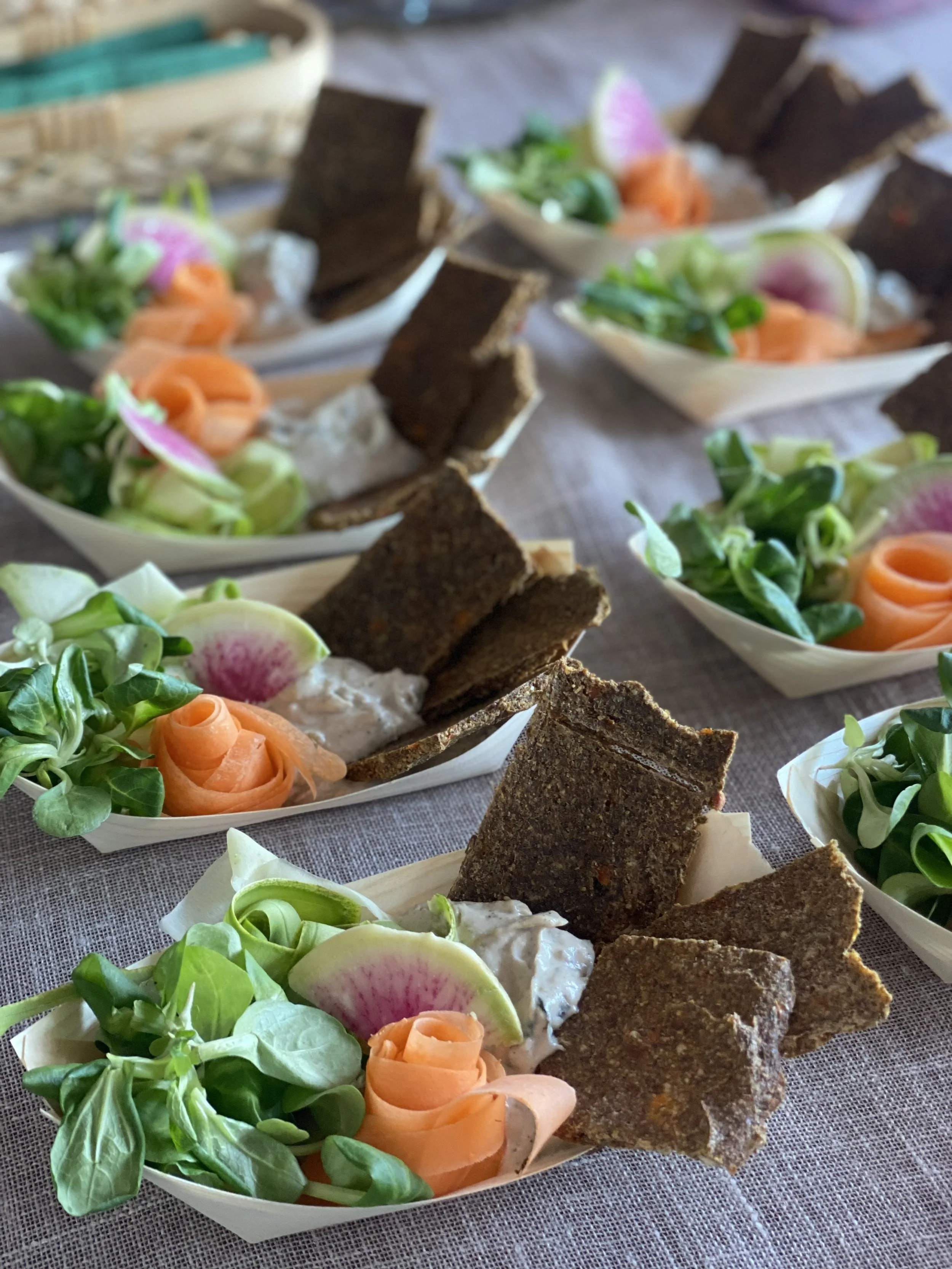 Several boats of smoked salmon, cream cheese, watercress, radish slices, and crispbread crackers on a table.