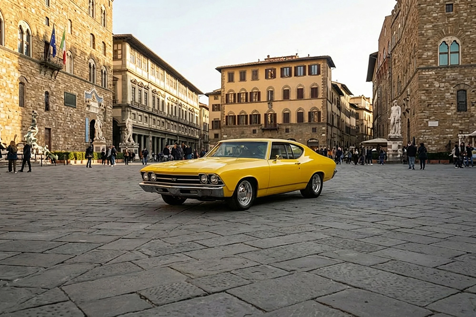 A vintage yellow muscle car parked on cobblestone pavement in a historic European city square surrounded by old stone buildings and statues, with people walking in the background.