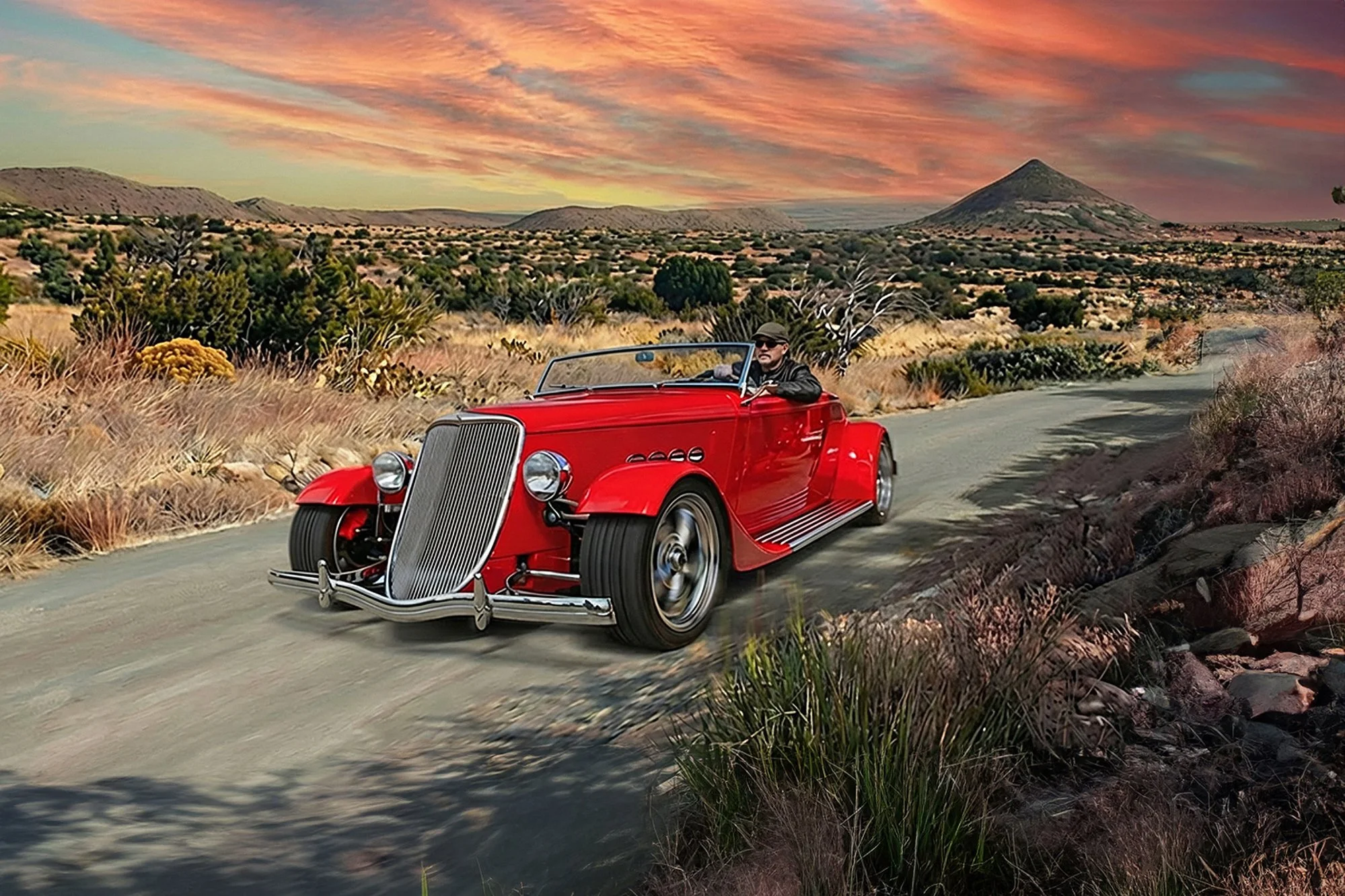 A red vintage car driving along a desert road during sunset, with cacti and dry vegetation in the foreground and rolling hills and a conical mountain in the background.